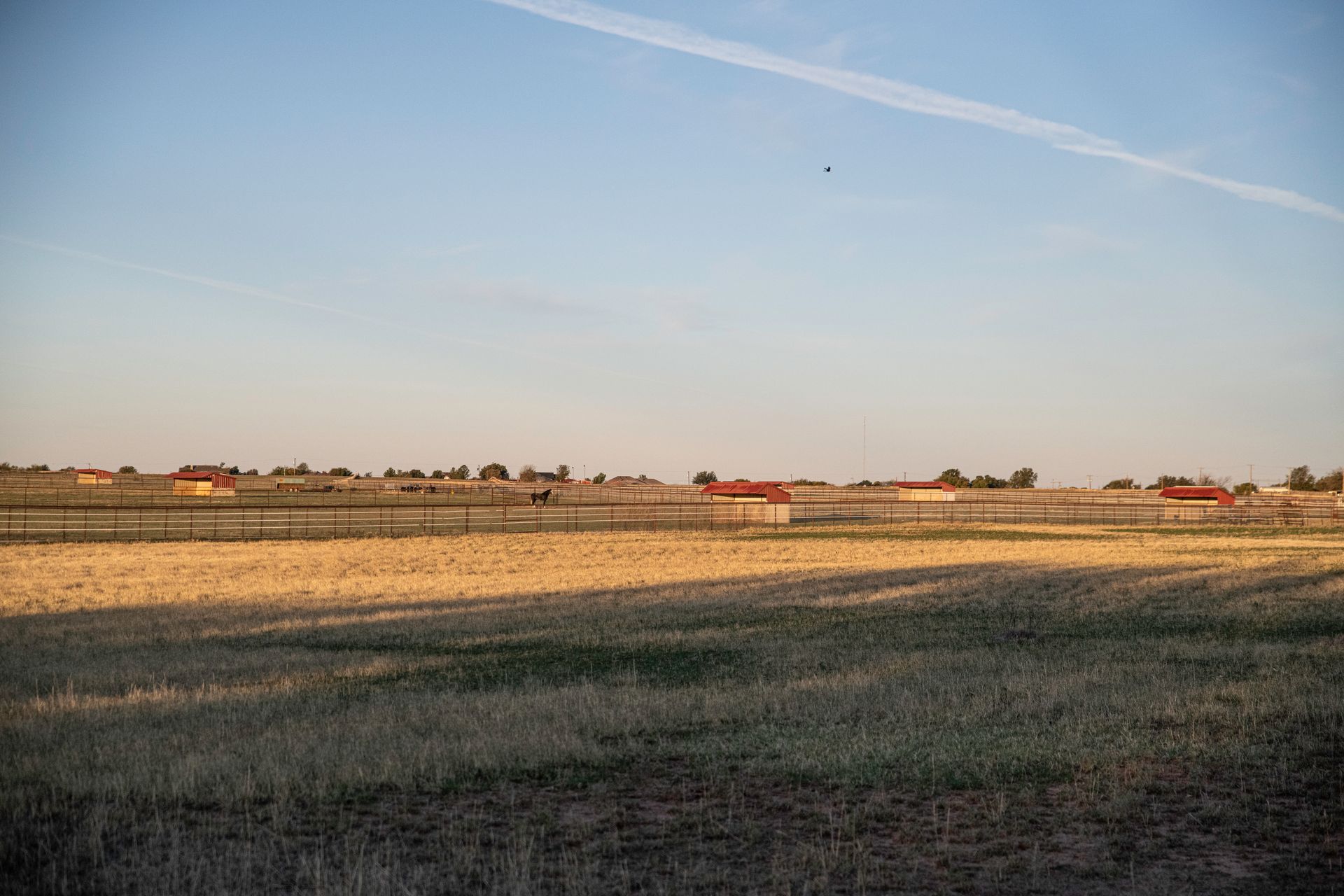 a fenced in field with a blue sky in the background