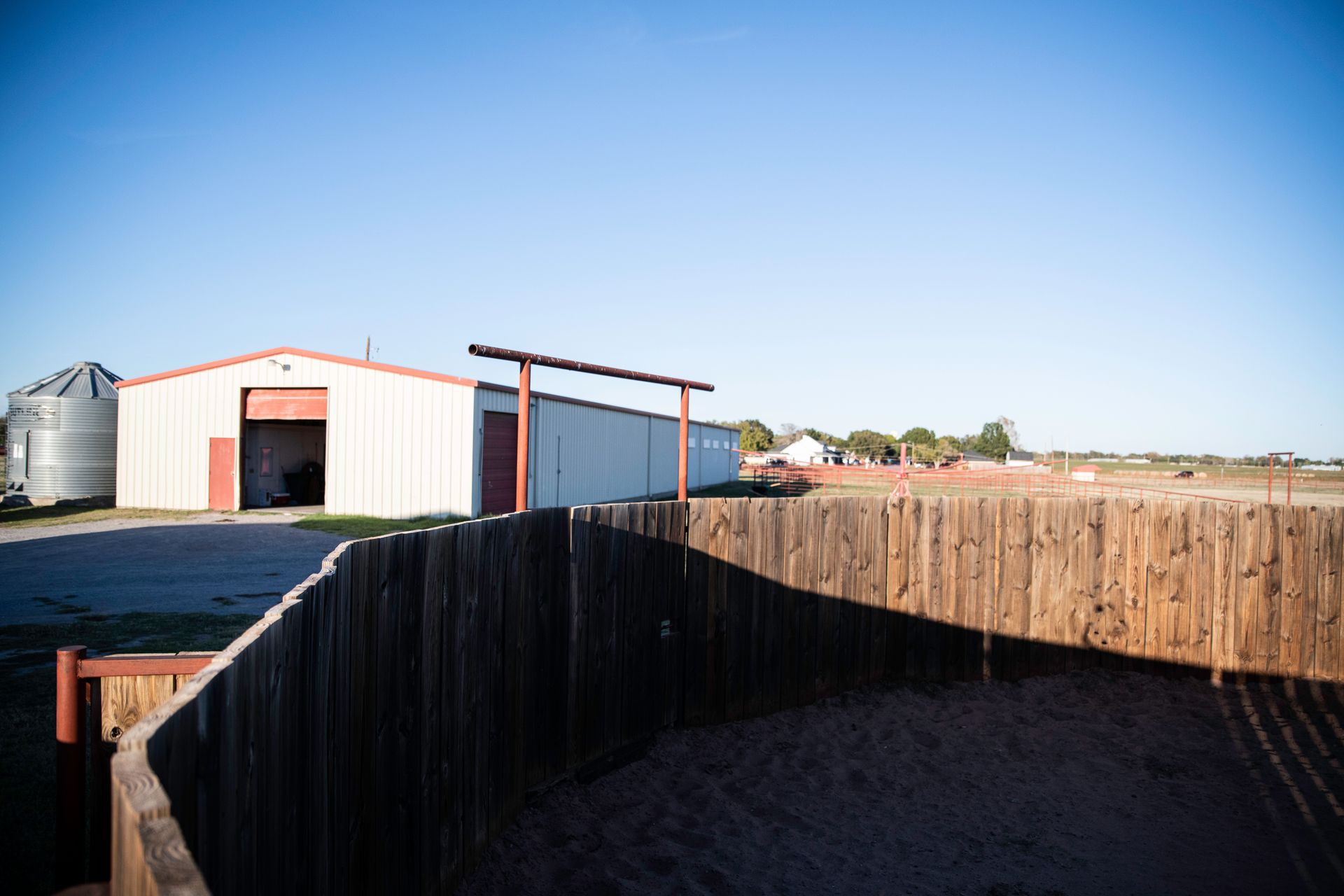 a white building with a red door is behind a wooden fence .