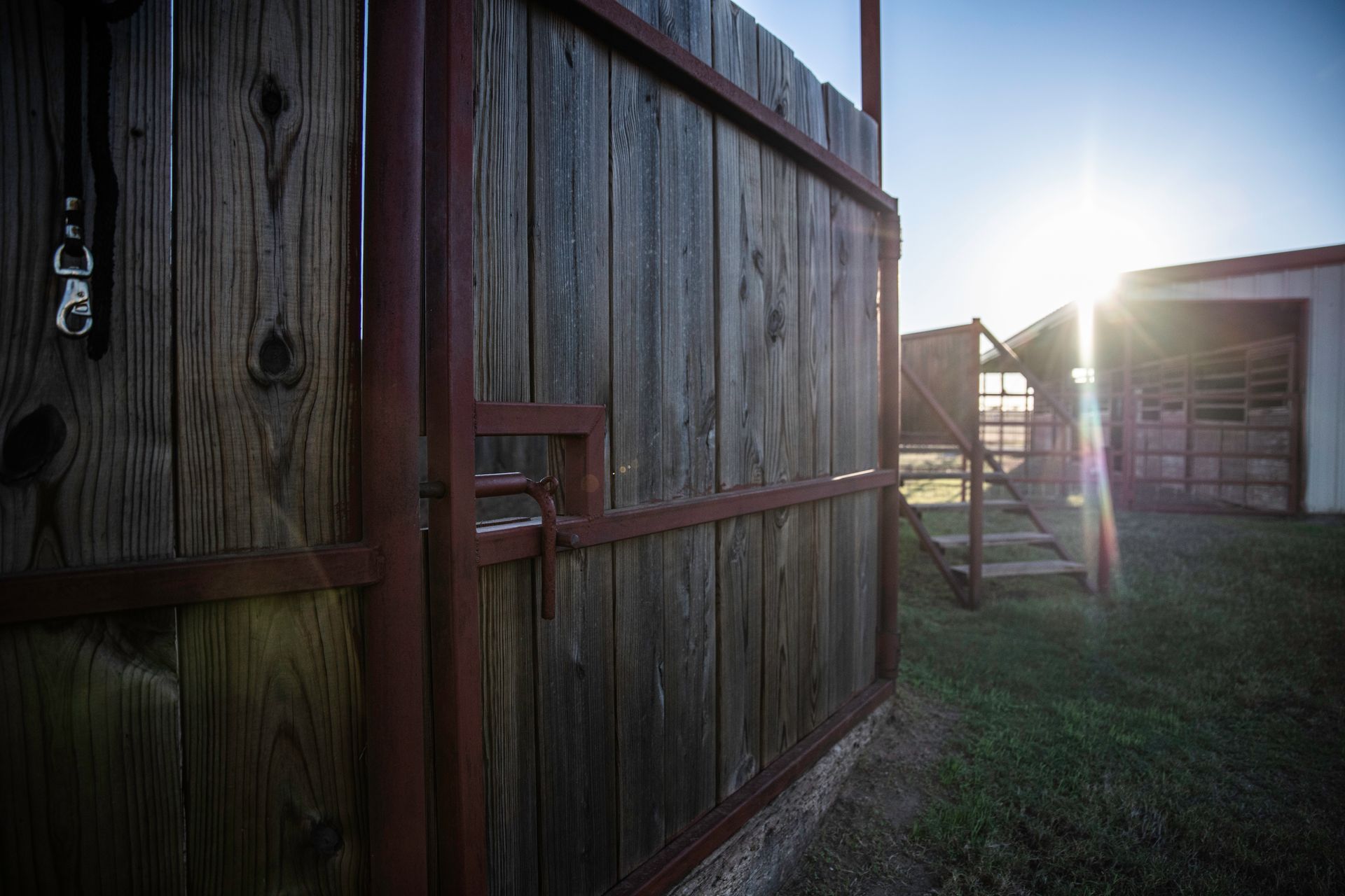 a wooden fence with stairs leading up to it and the sun shining through it .