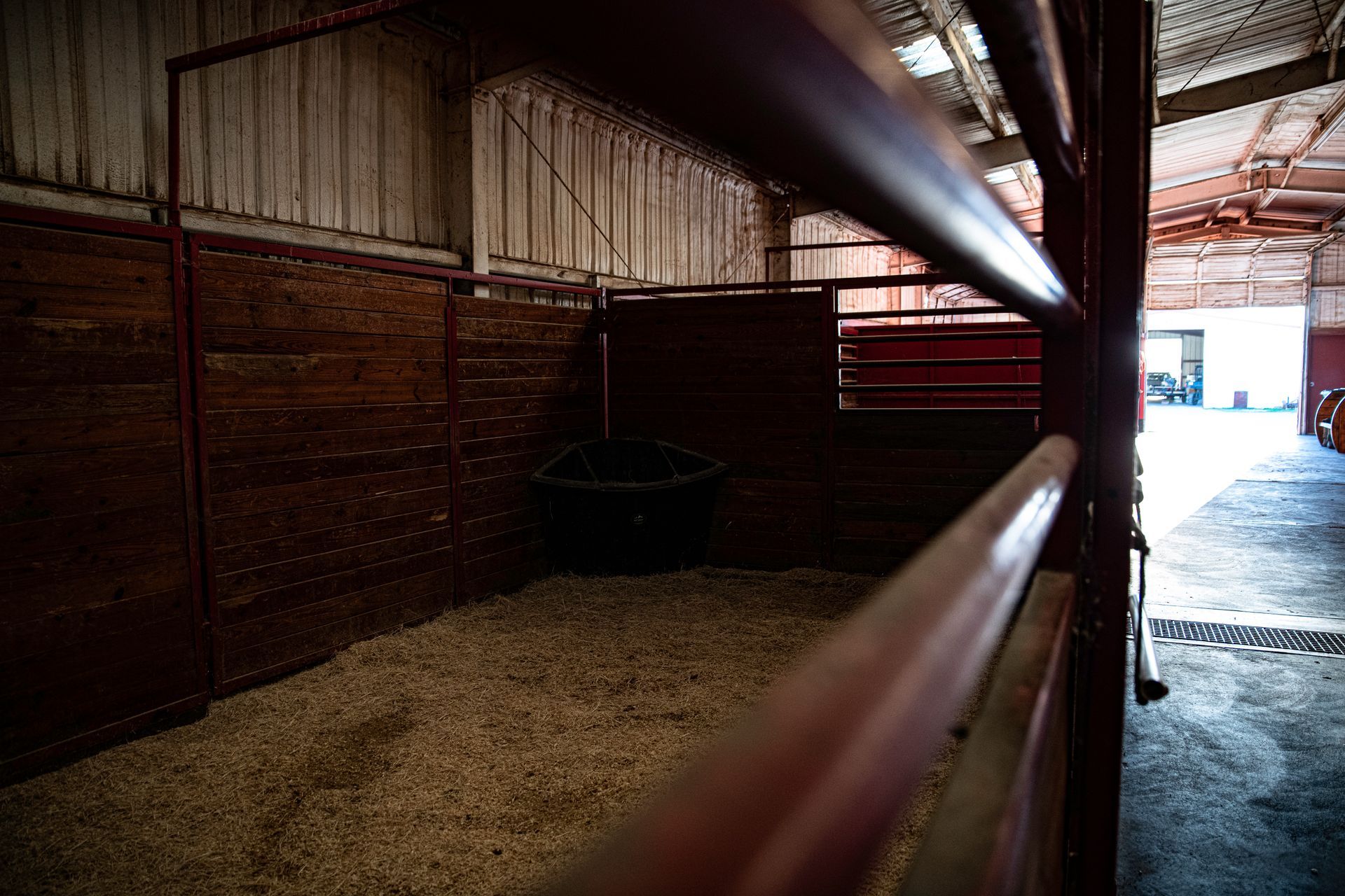 an empty stable with a fence and a brick wall .