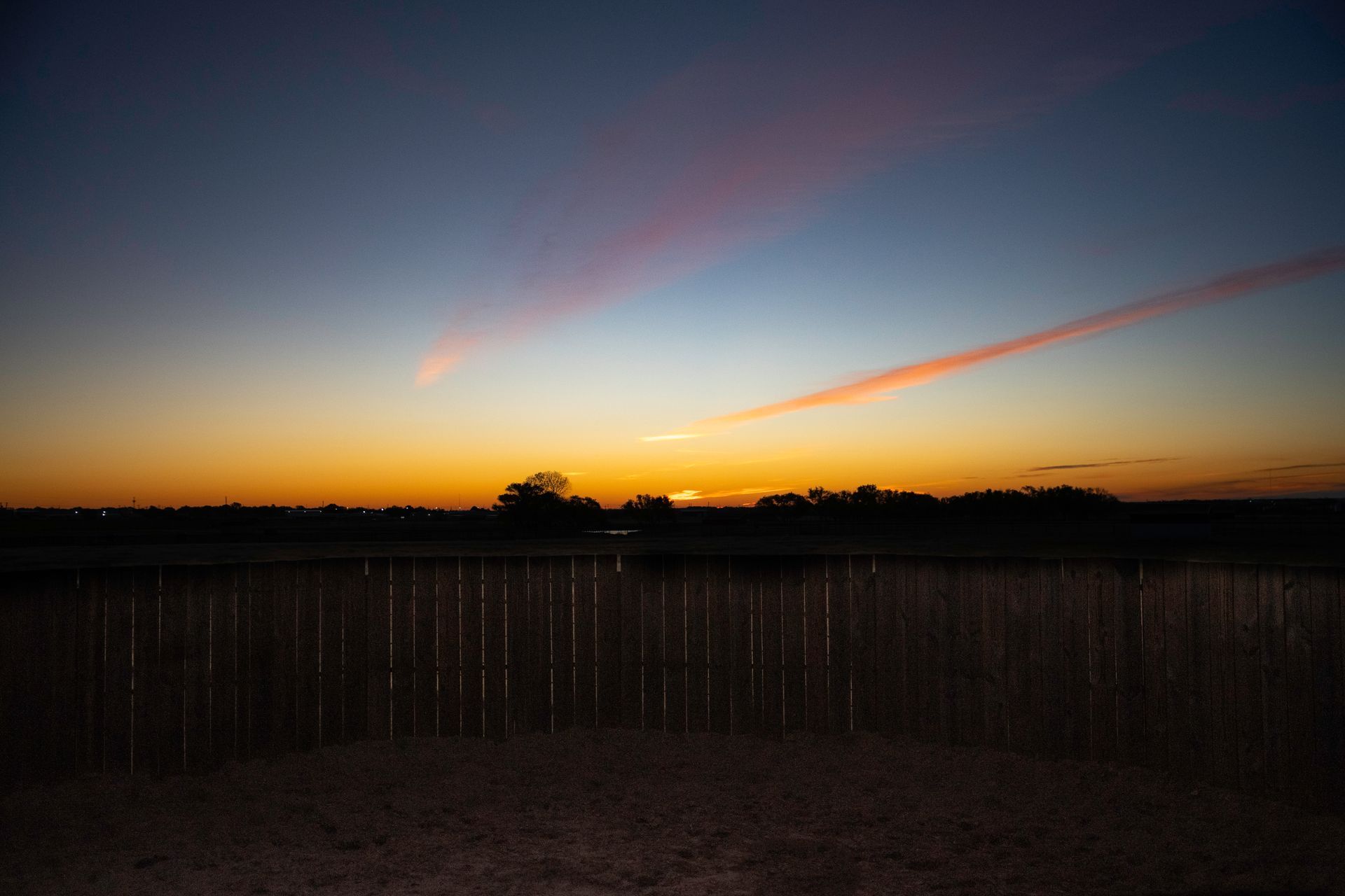 a sunset with a fence in the foreground
