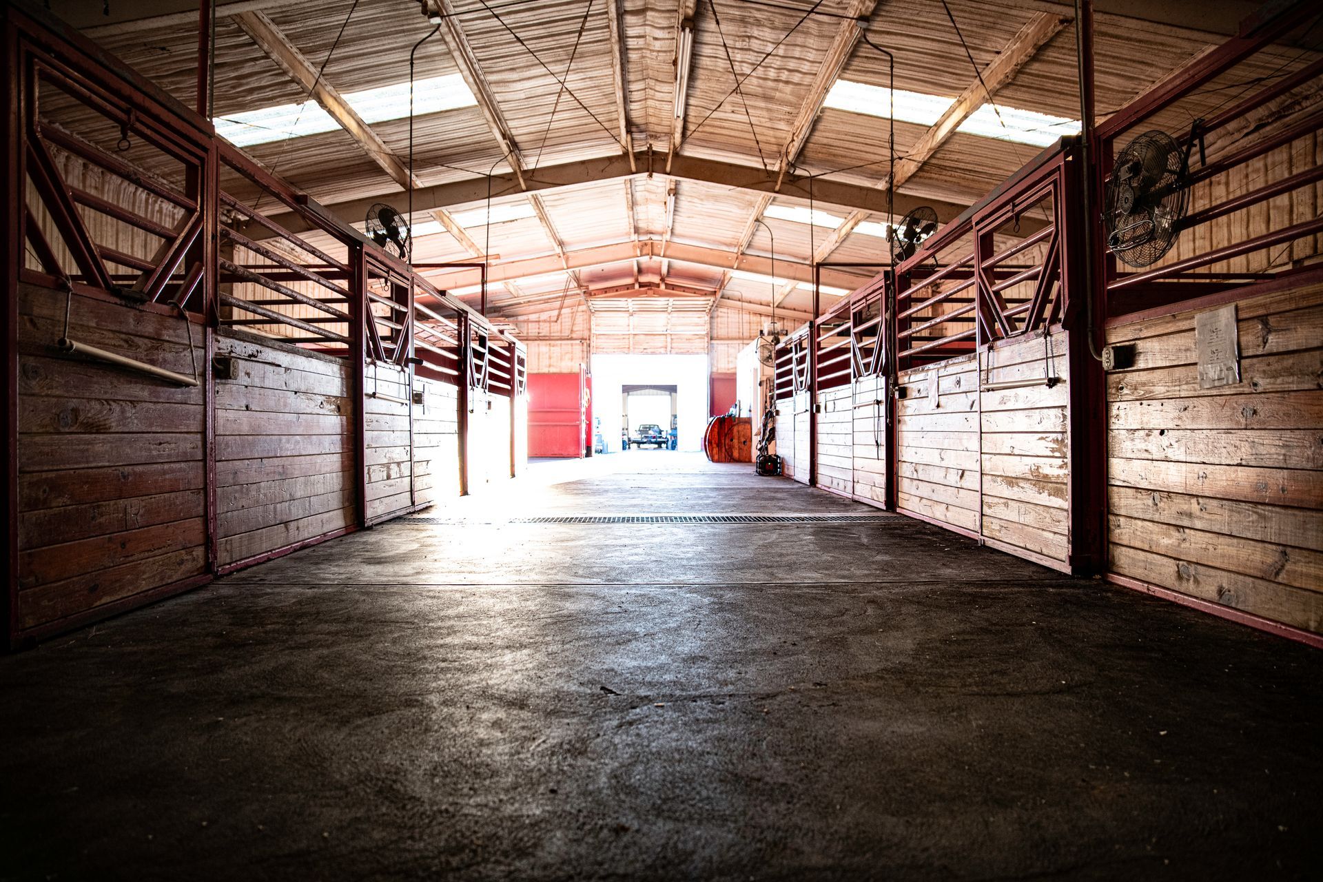 a large empty stable with a lot of horses in it .