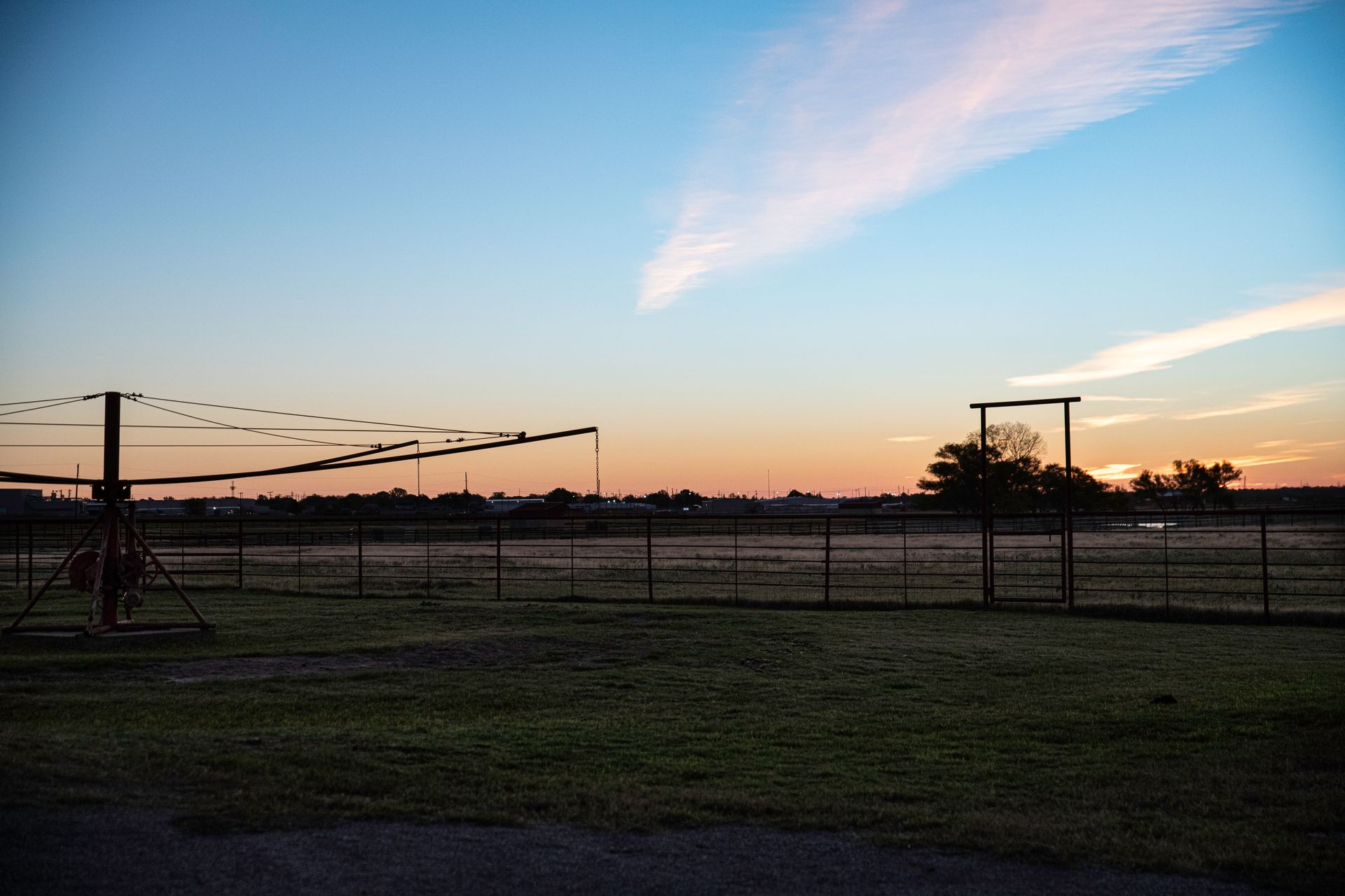 a field with a fence and a sunset in the background .