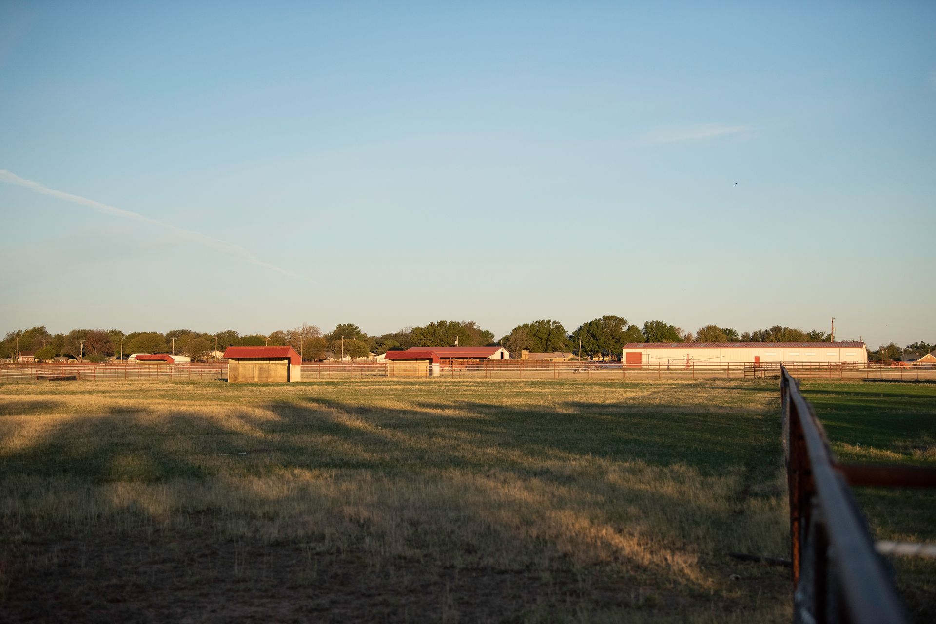 a field with a fence in the foreground and a building in the background .