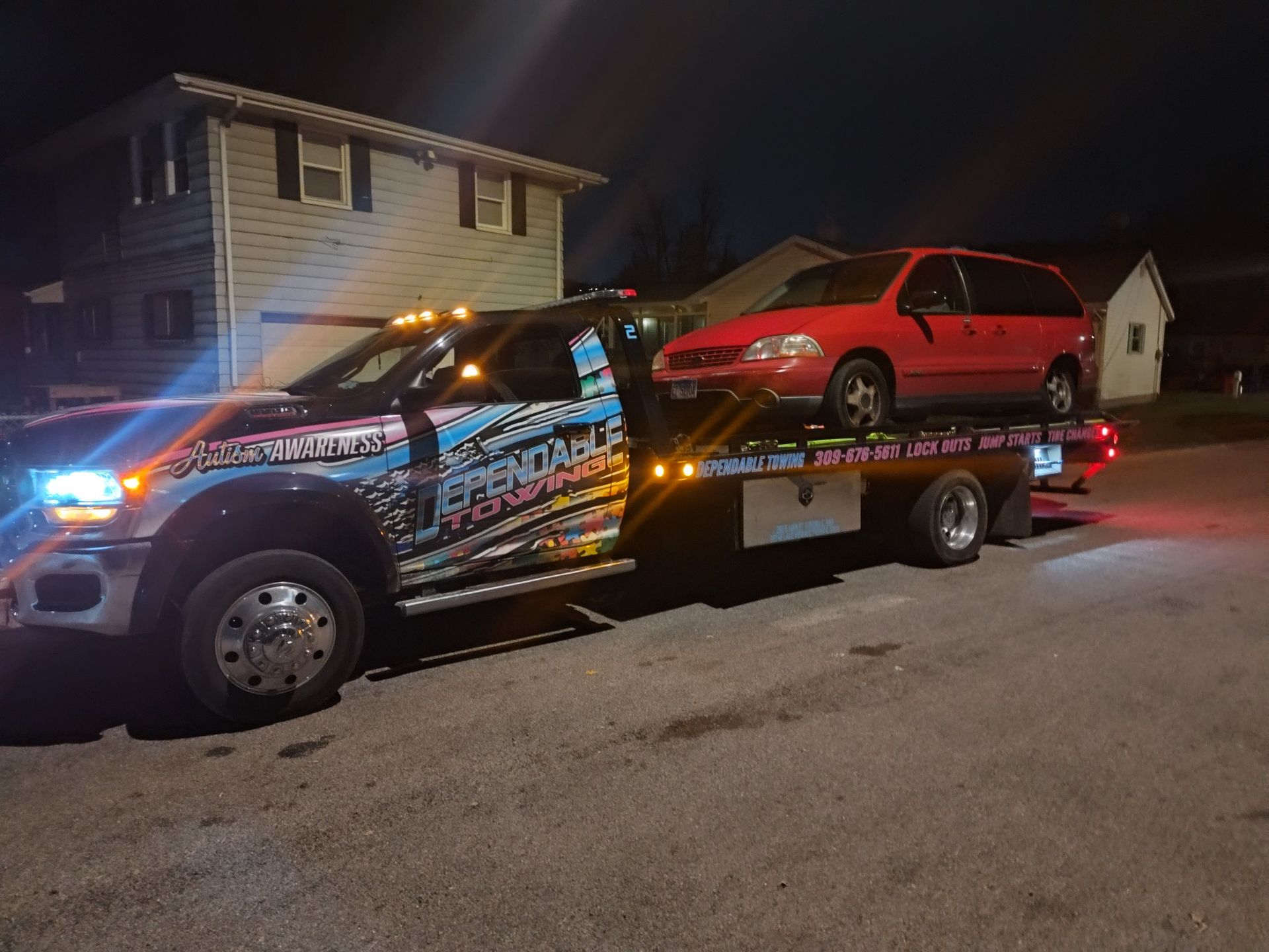 A tow truck with a red van on top of it
