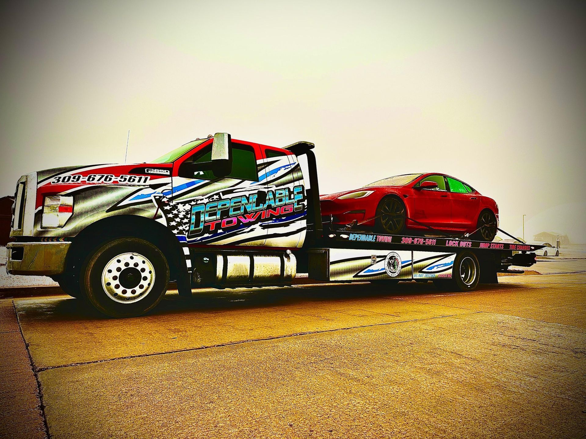 A tow truck is carrying a red car on the back of it.