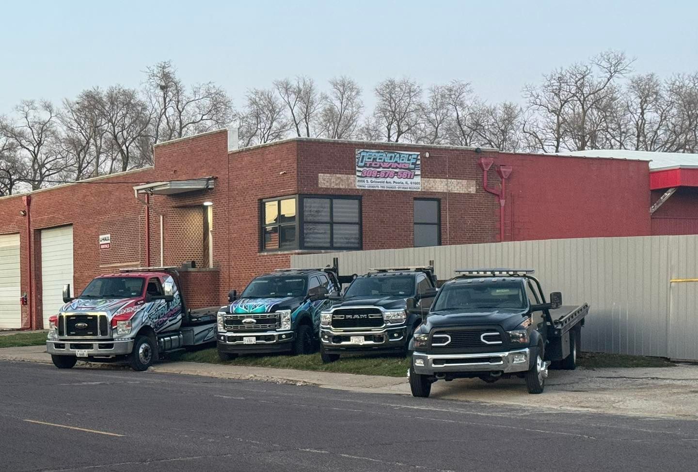 A row of tow trucks parked in front of a building.