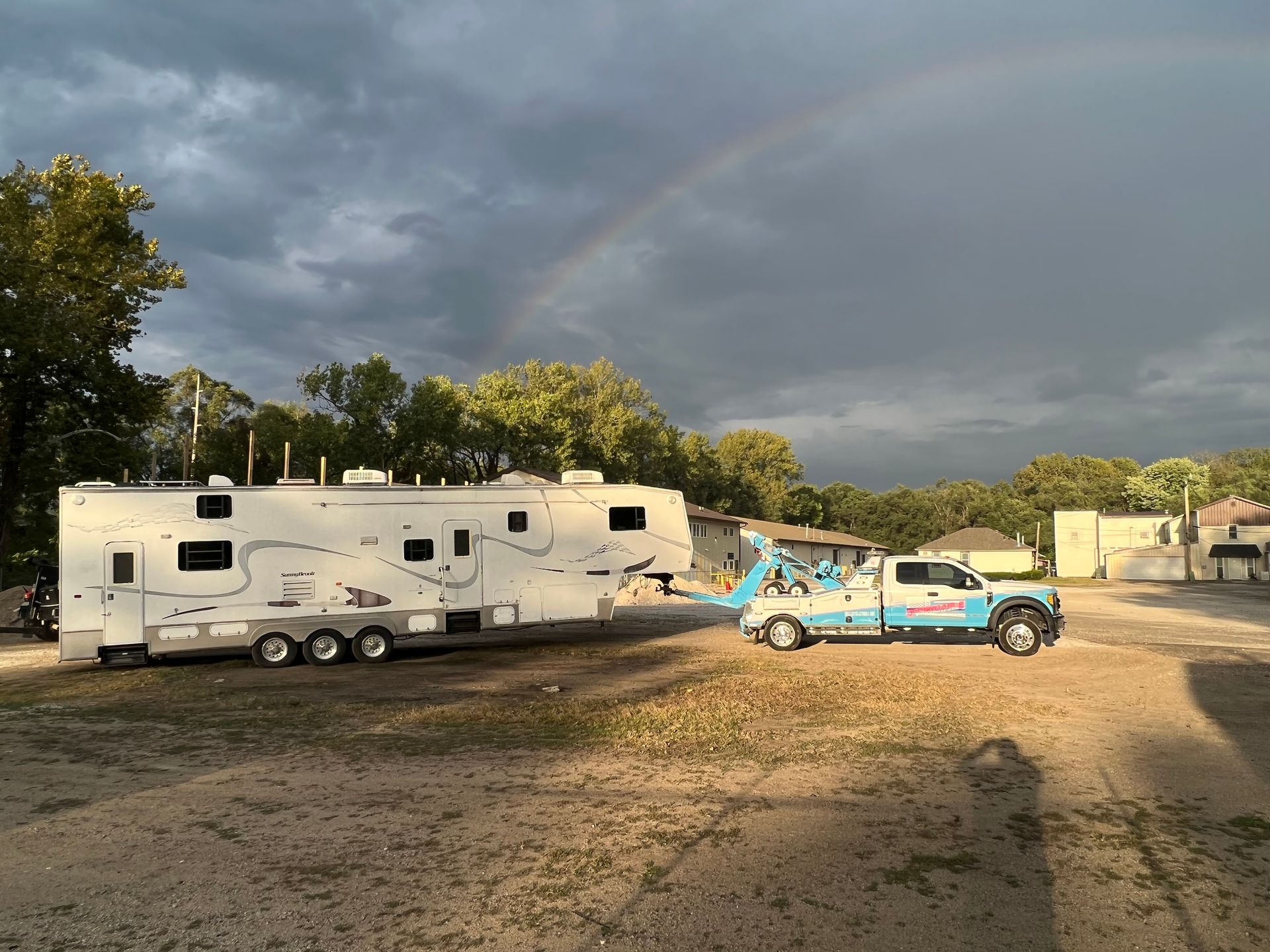 A rv is being towed by a tow truck in a parking lot.