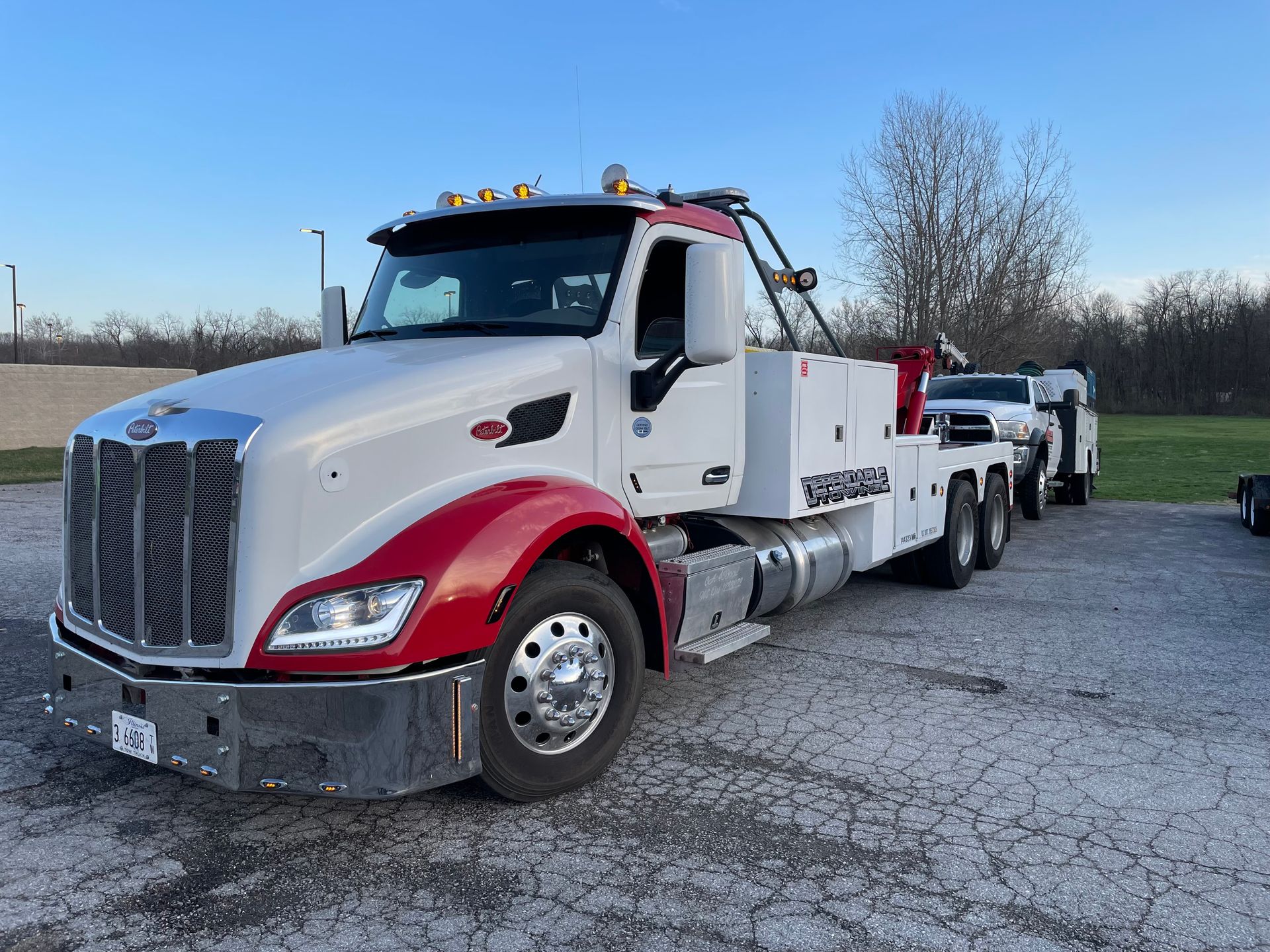 A white and red tow truck is parked in a parking lot.