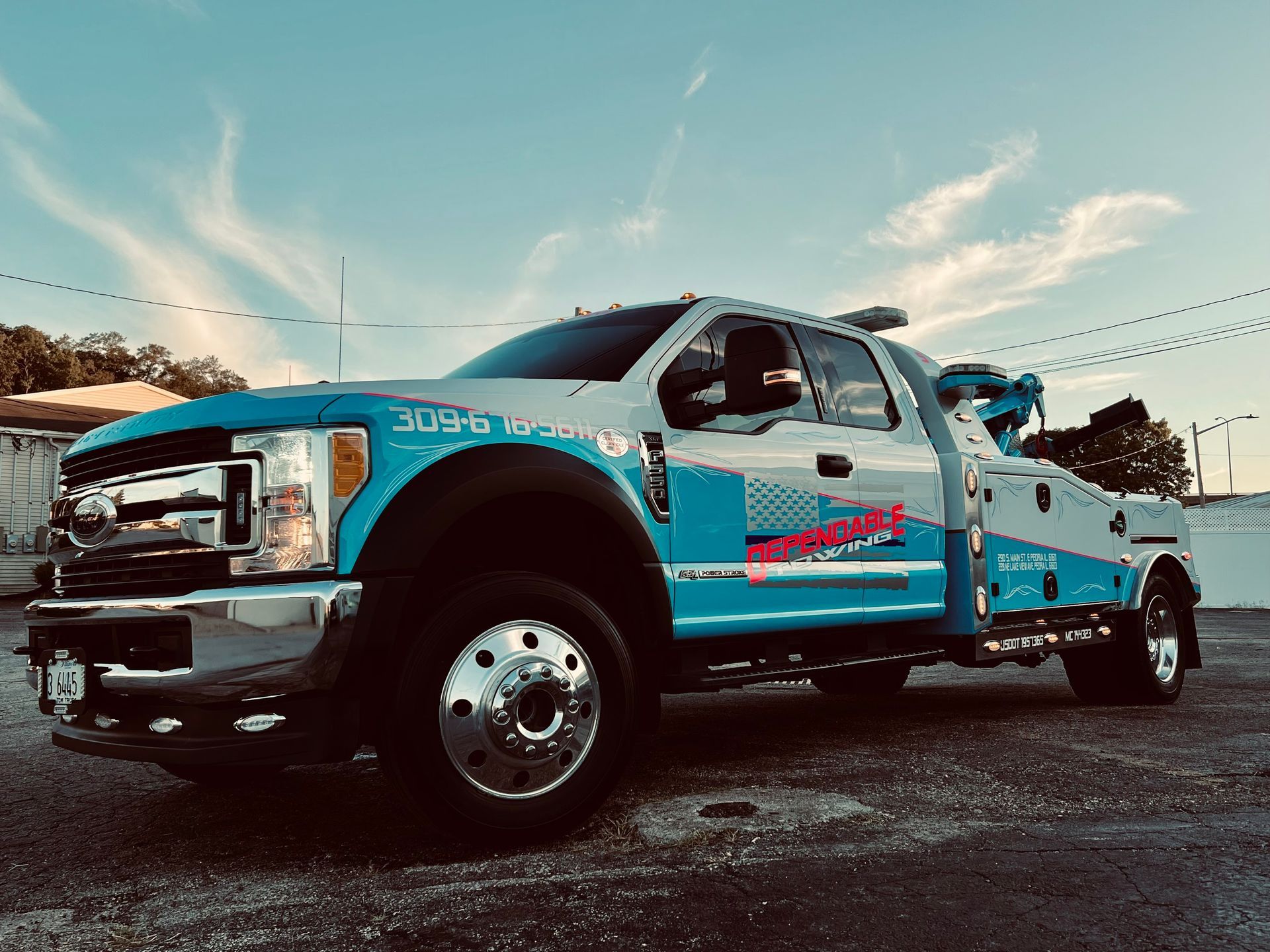 A blue and white tow truck is parked in a parking lot.