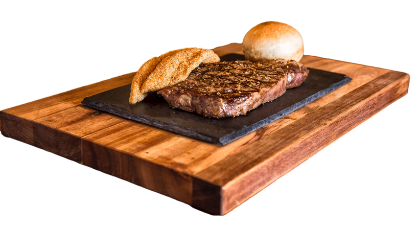 A steak and a bun are on a wooden cutting board.