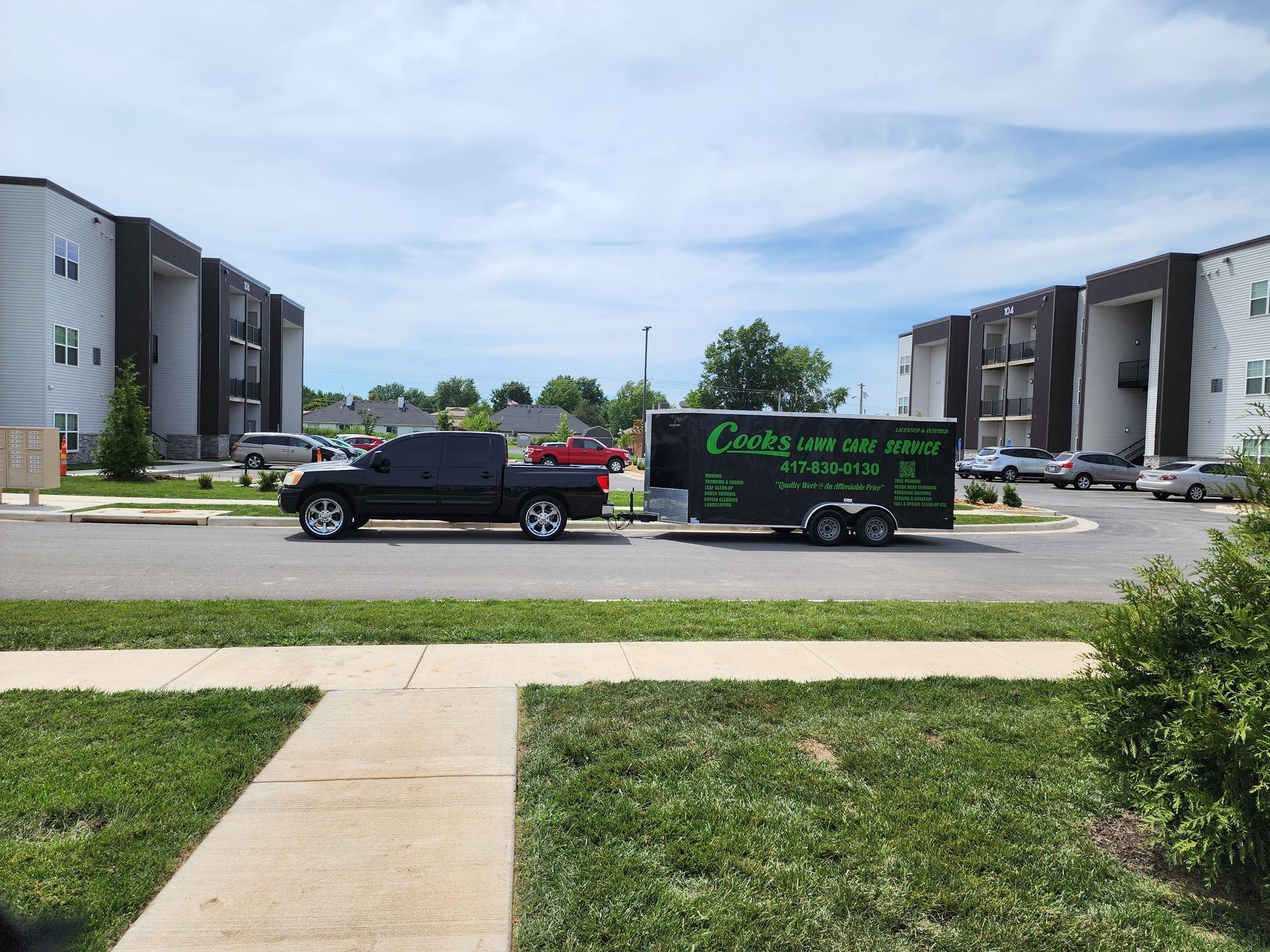 A truck and trailer are parked on the side of the road in front of a building.