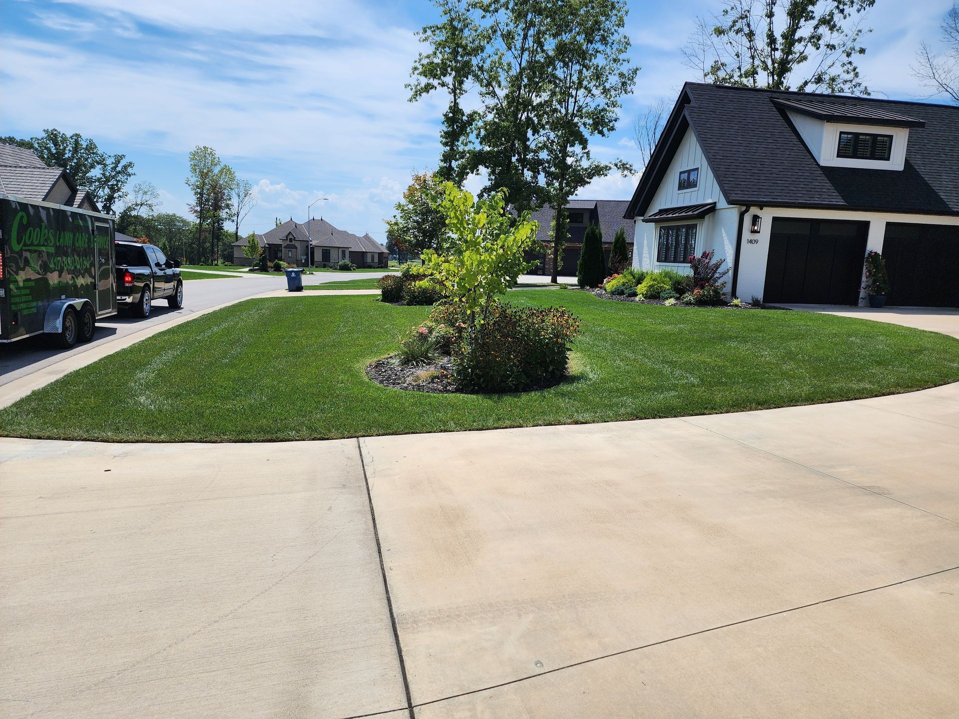 A white house with a black roof and a trailer parked in front of it.