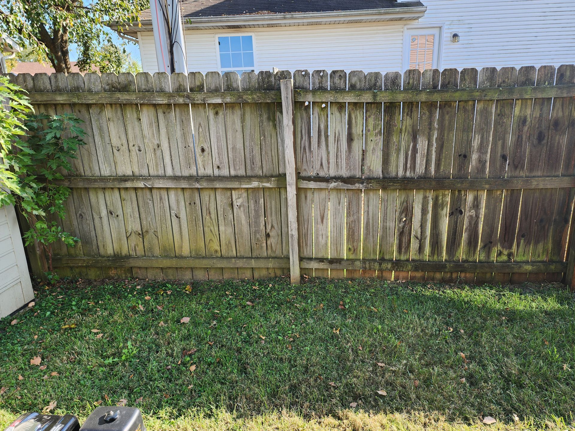 A wooden fence is sitting in the grass in front of a house.