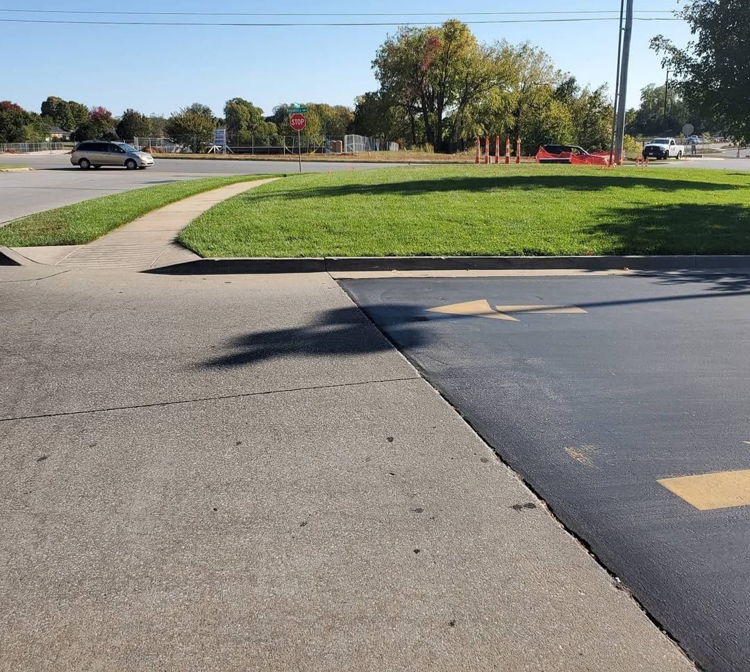 A car is driving down a street next to a grassy area