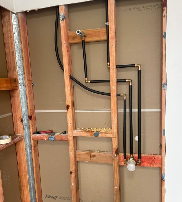 A Wooden Frame With Pipes Coming Out Of It — Russell Plumbing In Manunda, QLD