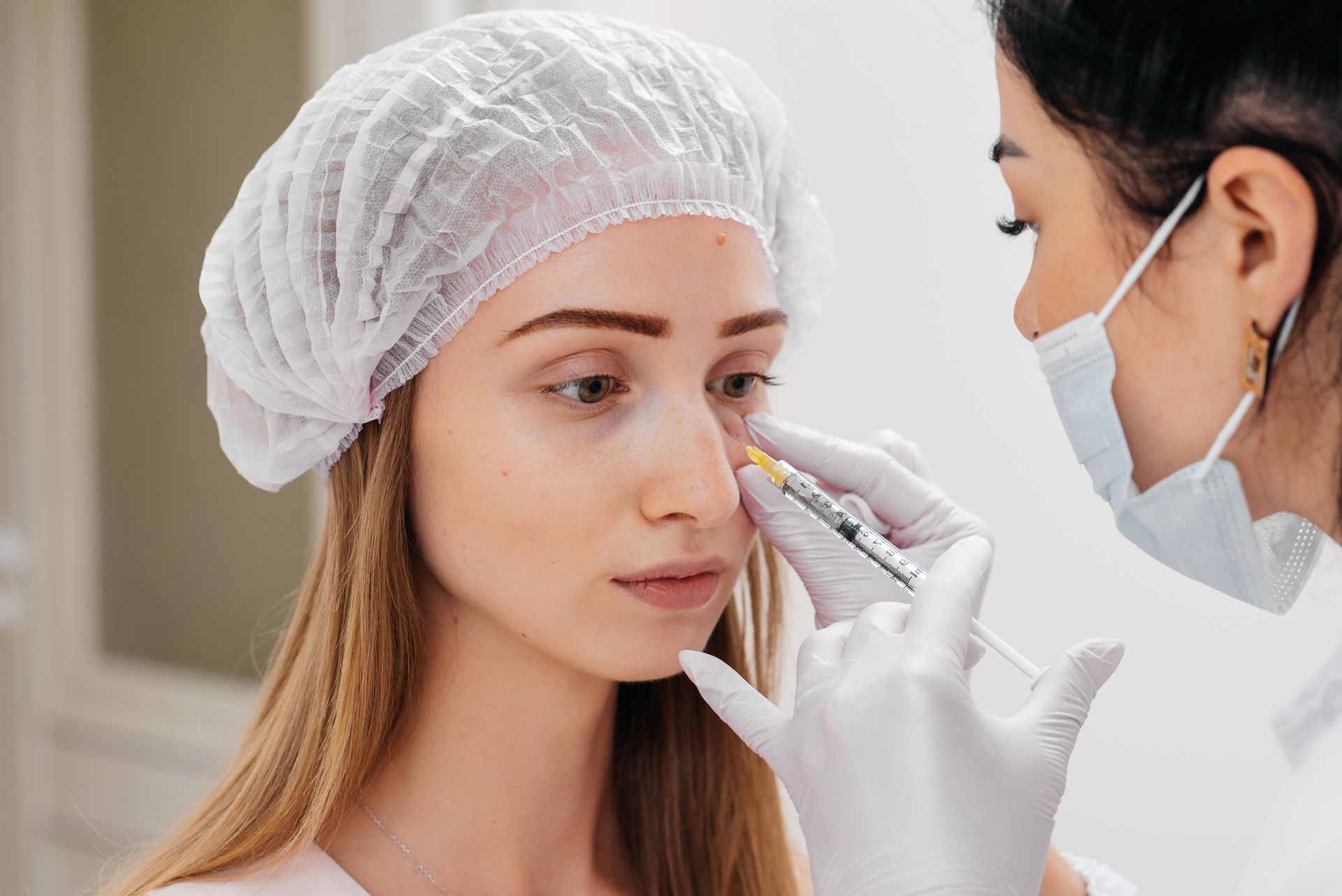 Woman receiving an injection near her eye from a medical professional, indoors.
