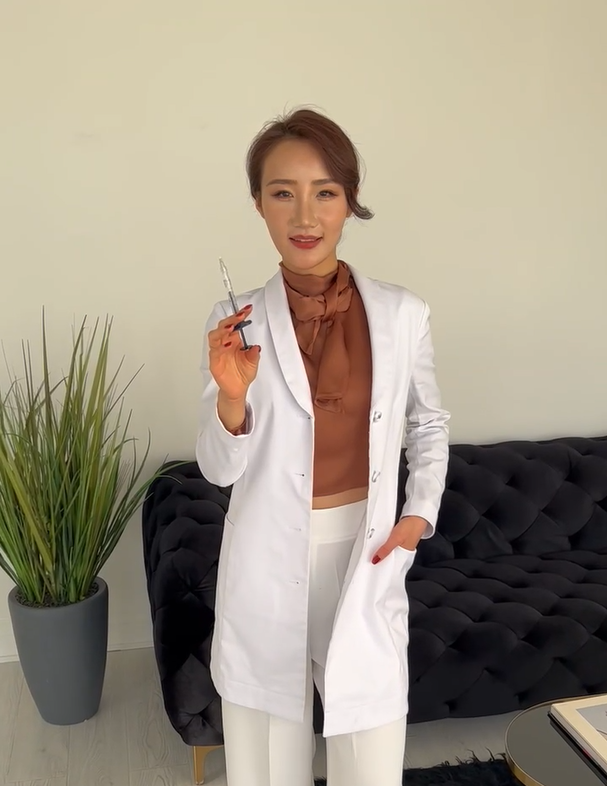 A woman in a lab coat is holding a syringe in her hand.