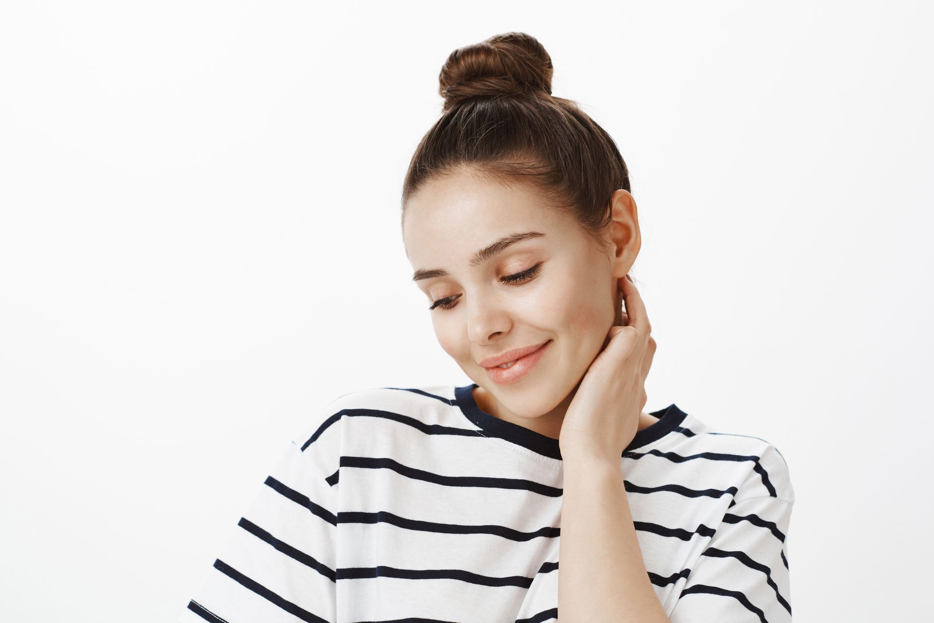 The woman is wearing a striped shirt and has her hair in a bun.