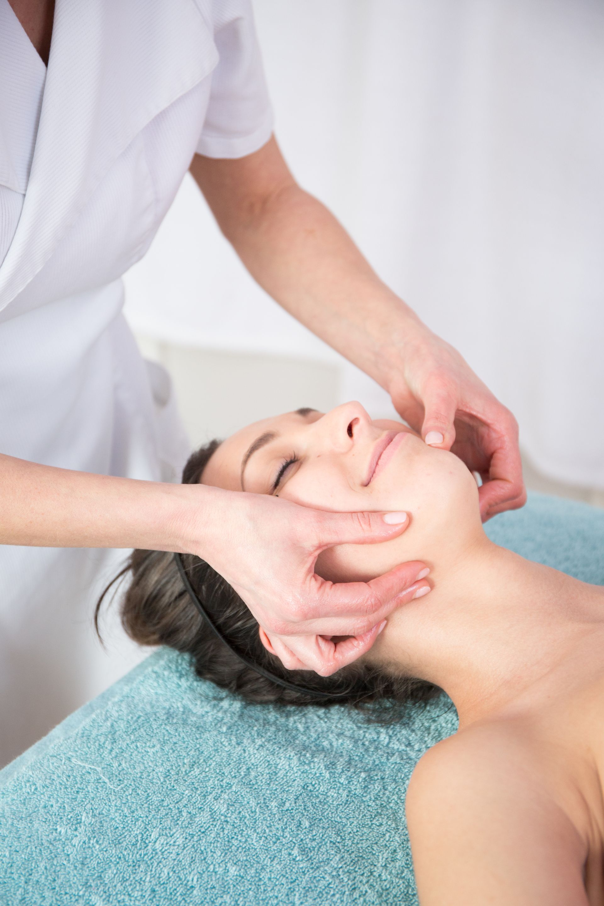 A woman is getting a facial massage at a spa.