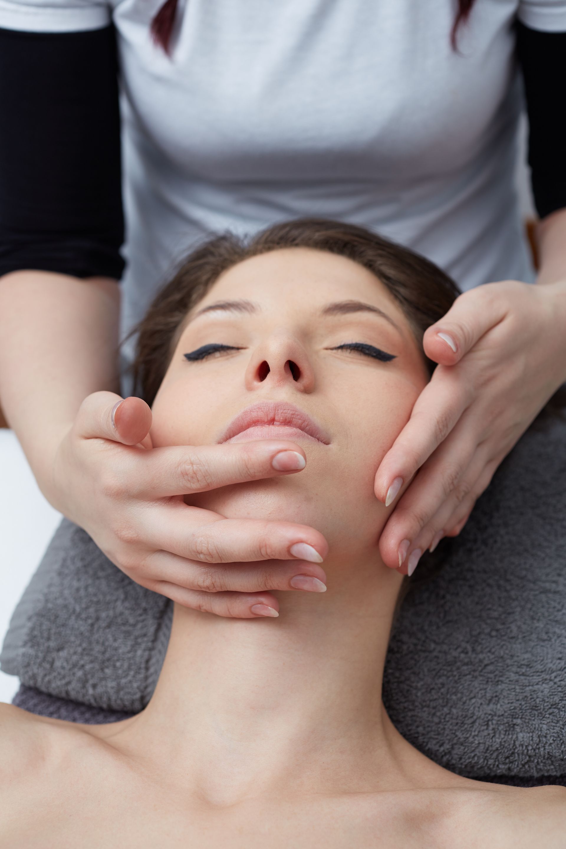 A woman is getting a facial massage at a spa.