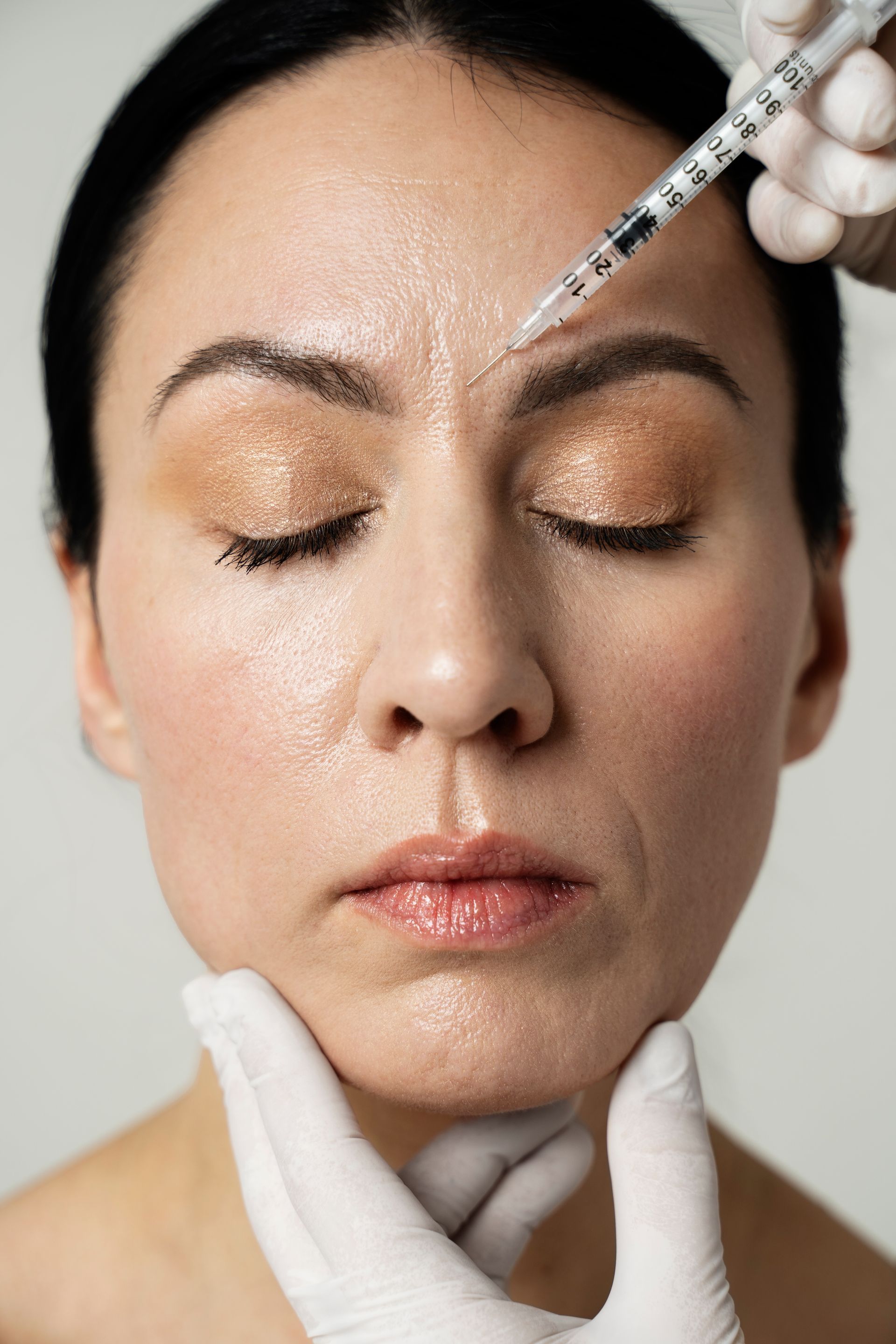 A woman is getting a botox injection in her forehead.