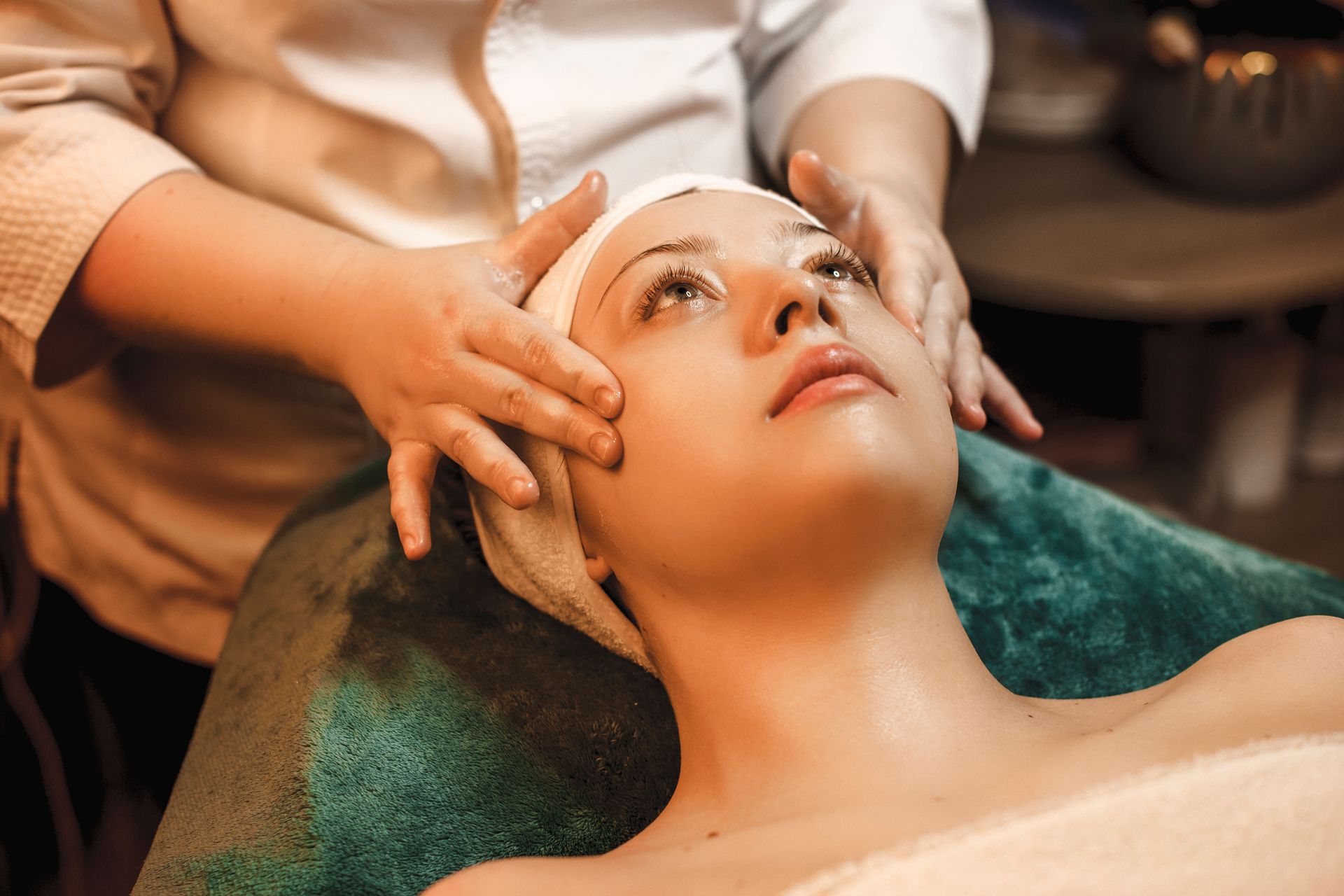 A woman is getting a facial massage at a spa.