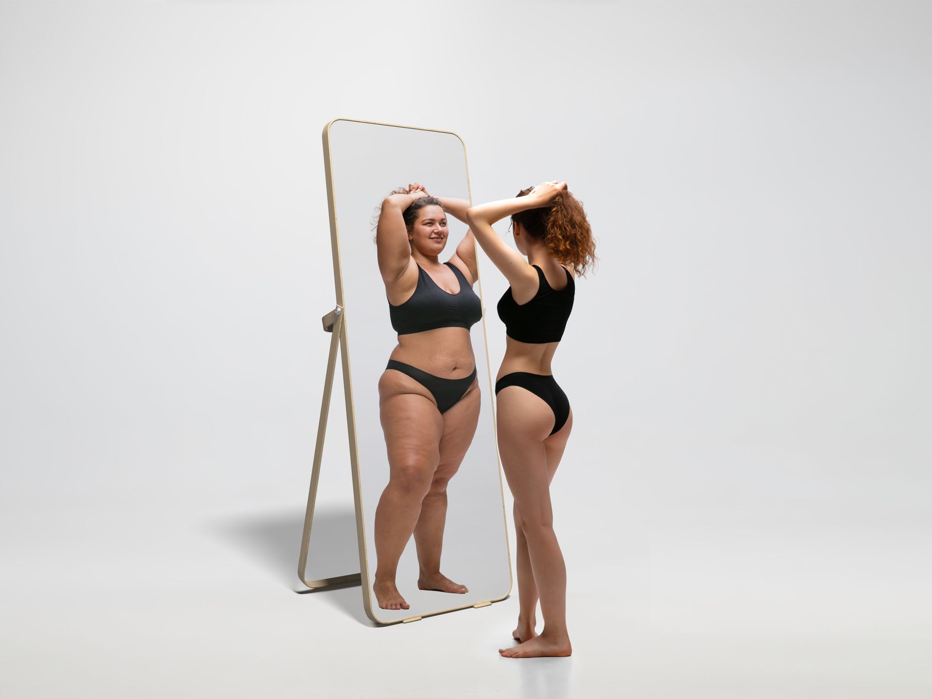 A woman is standing in front of a mirror looking at herself.