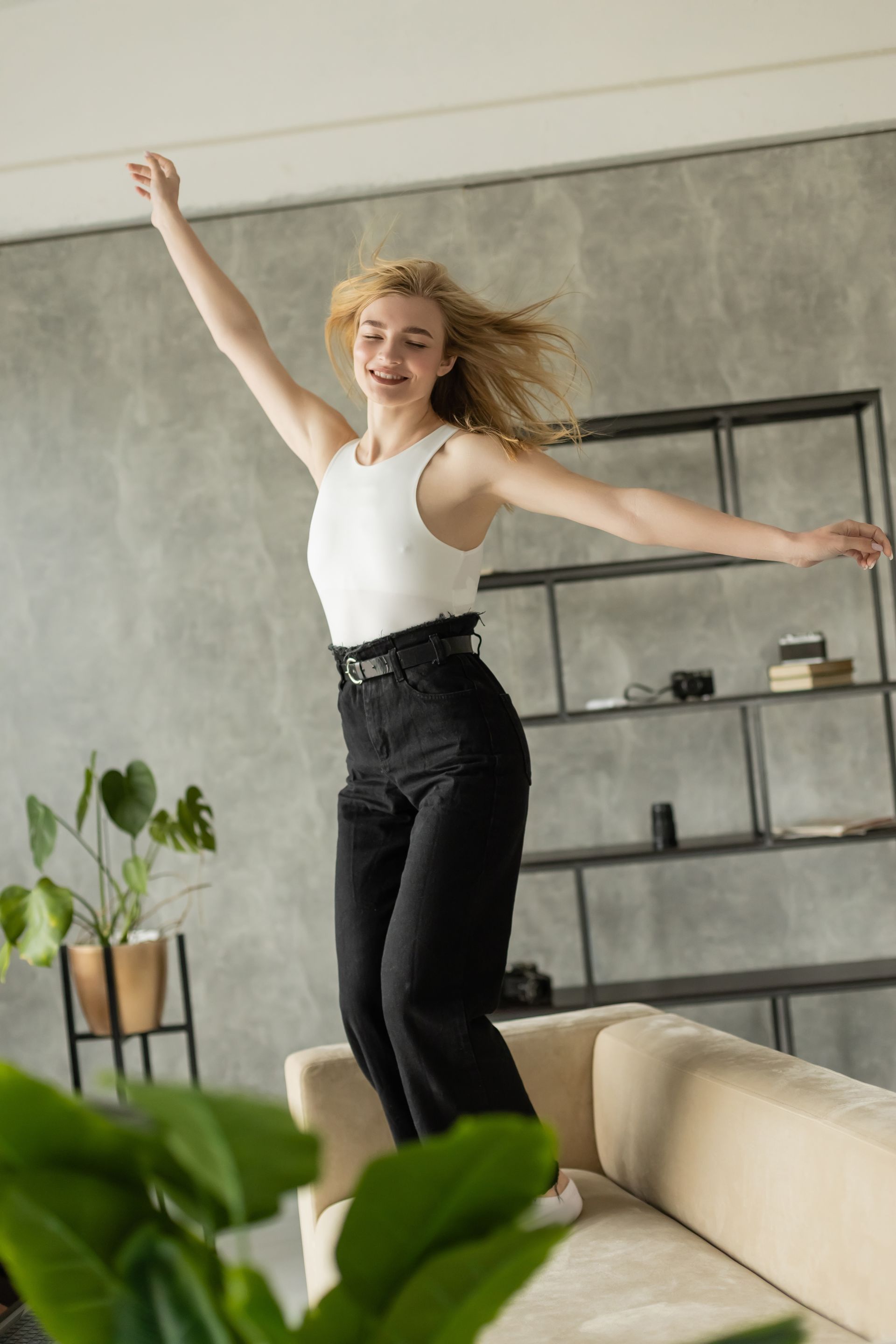 A woman is jumping on a couch in a living room.