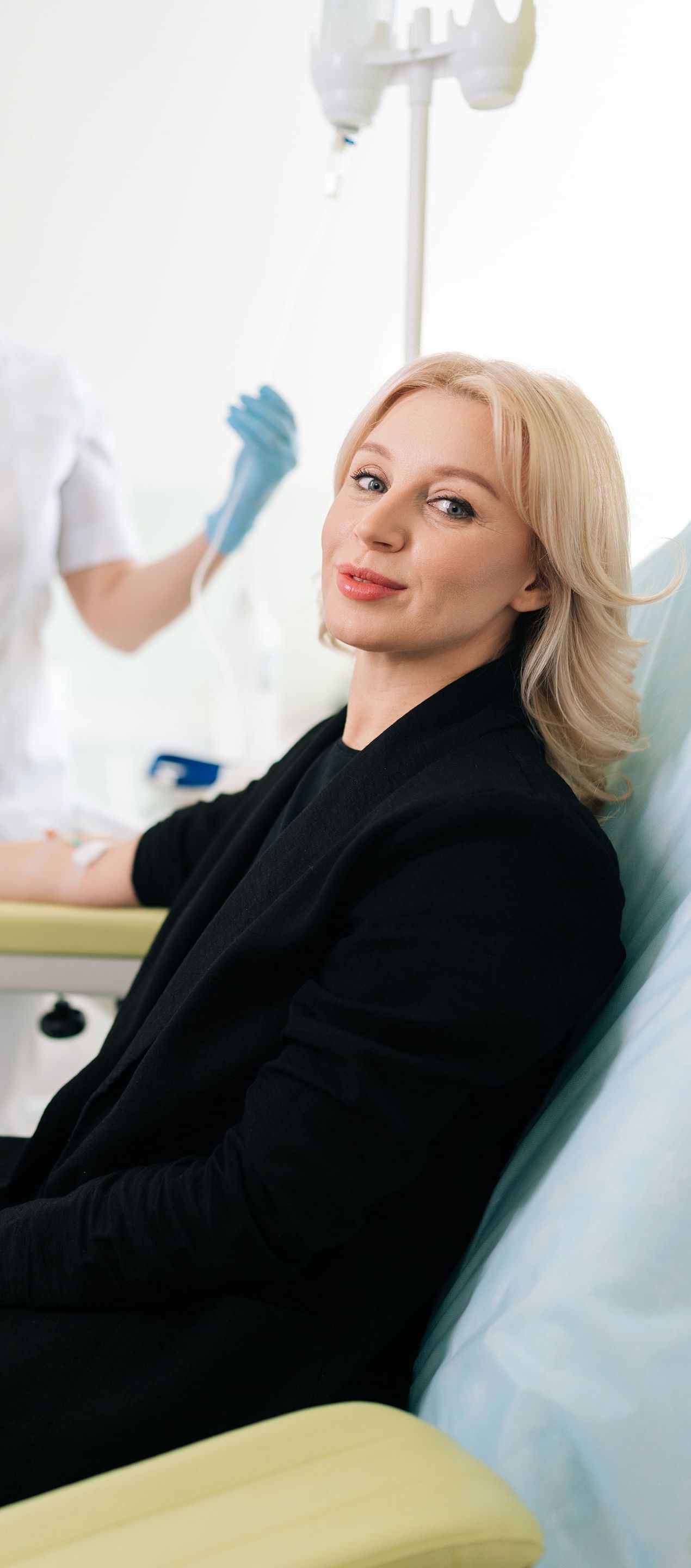 A woman is sitting in a chair with a nurse standing behind her.