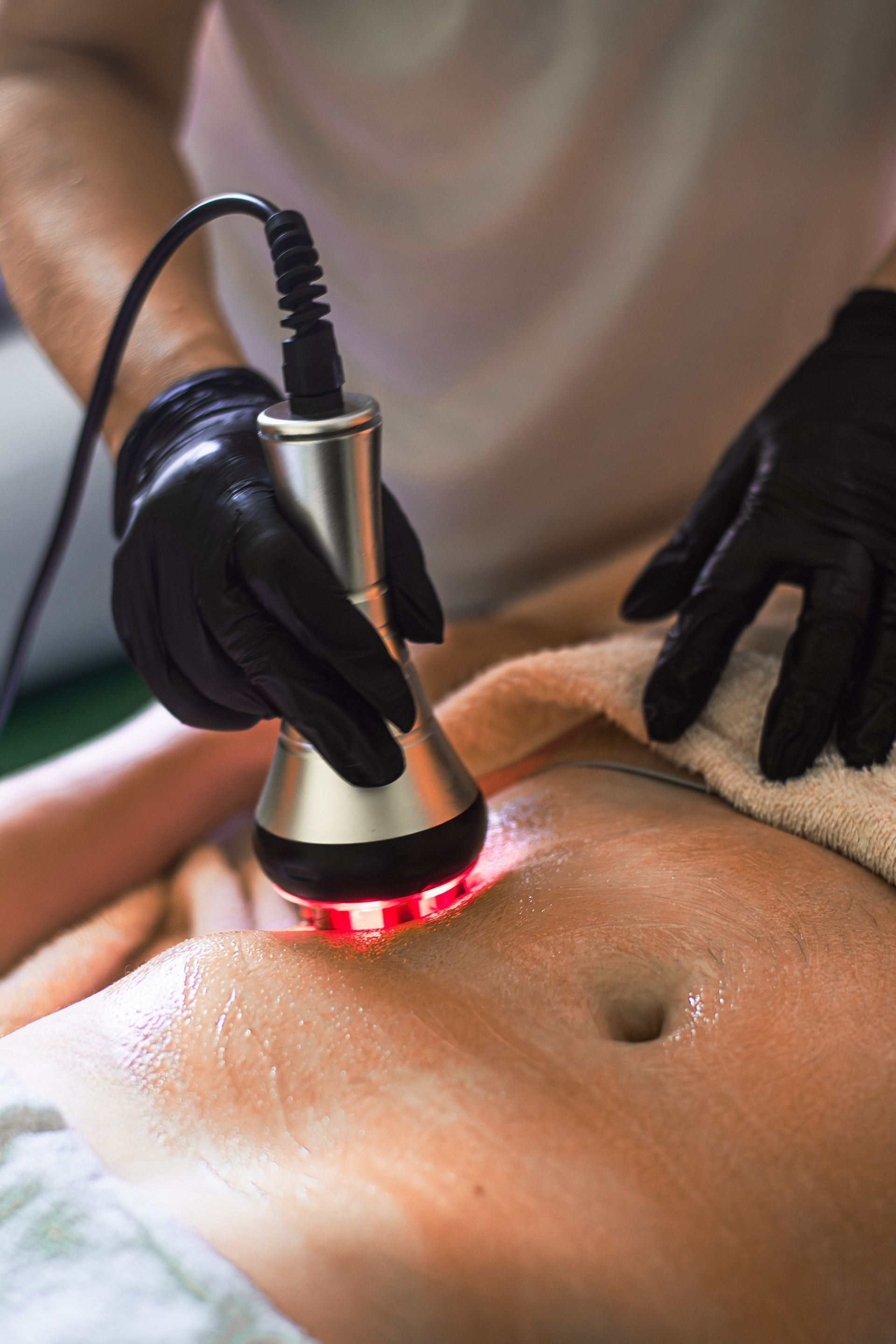 A woman is getting a cavitation treatment on her stomach.