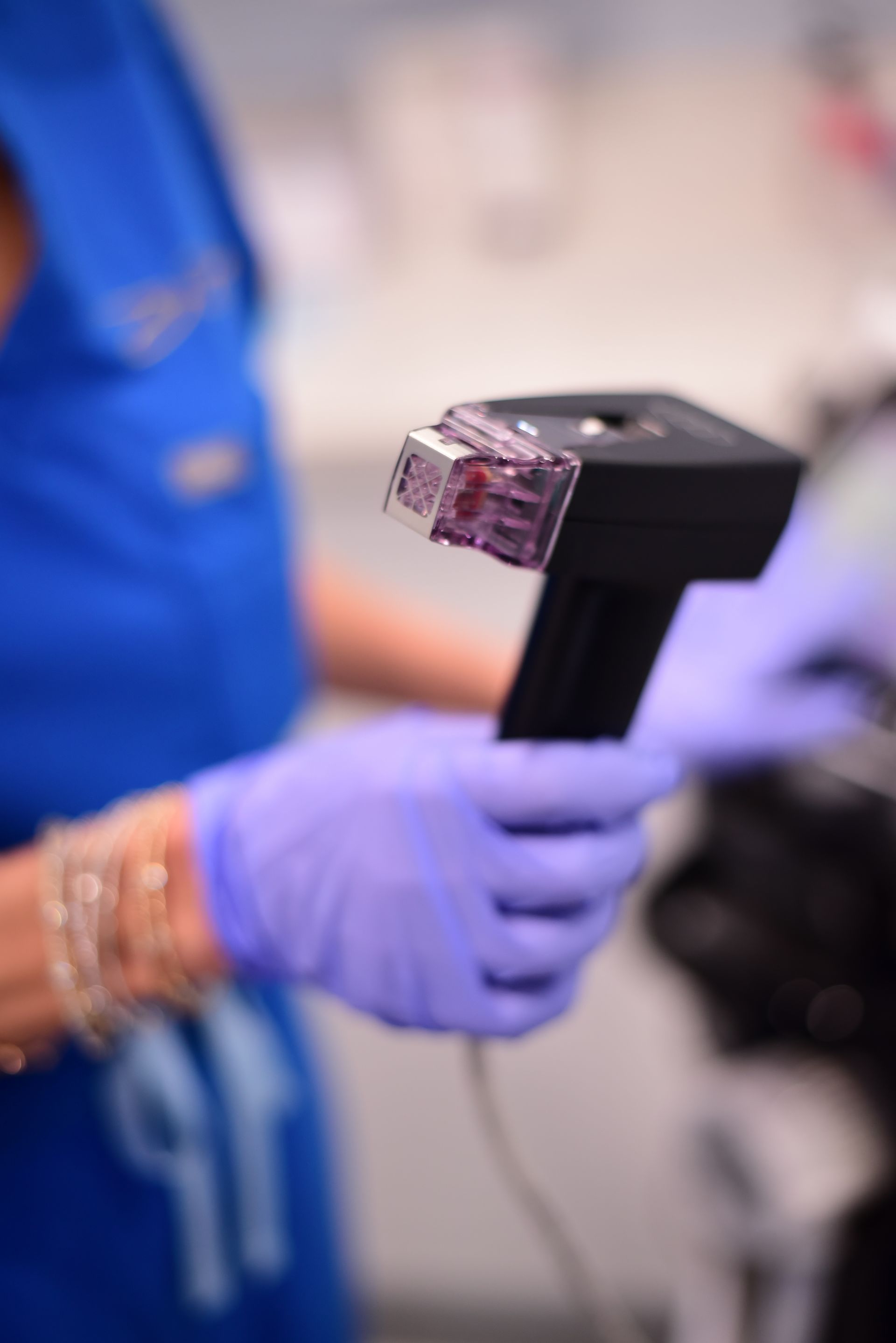 A person wearing purple gloves is holding a device in their hand.