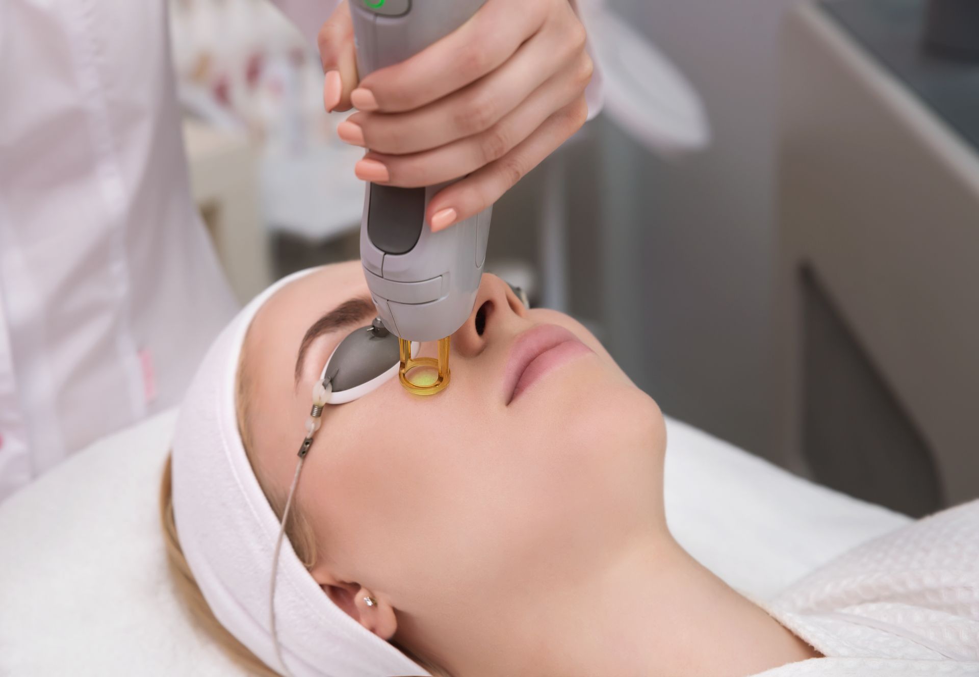 A woman is getting a laser treatment on her face.