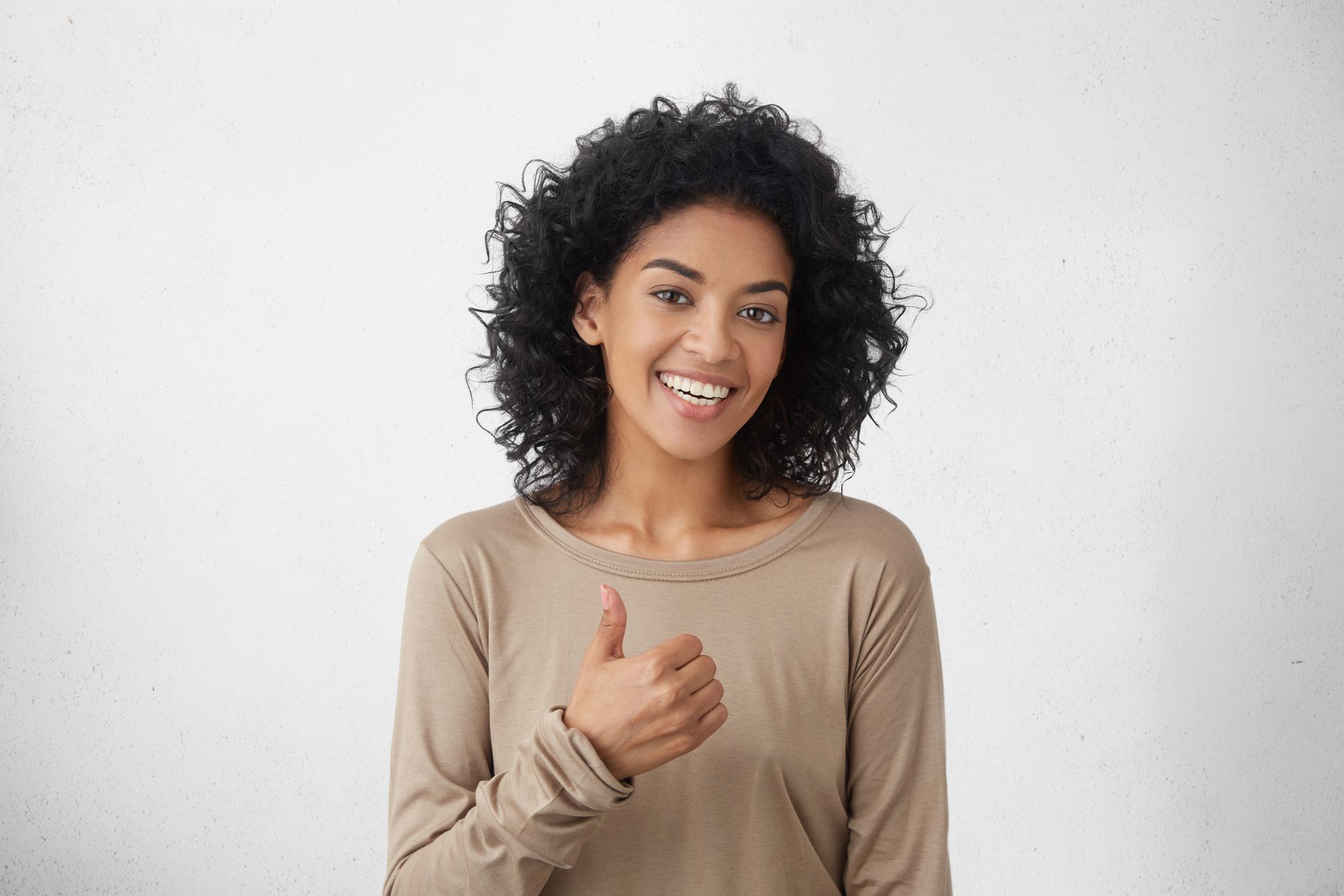 A woman is smiling and giving a thumbs up sign.