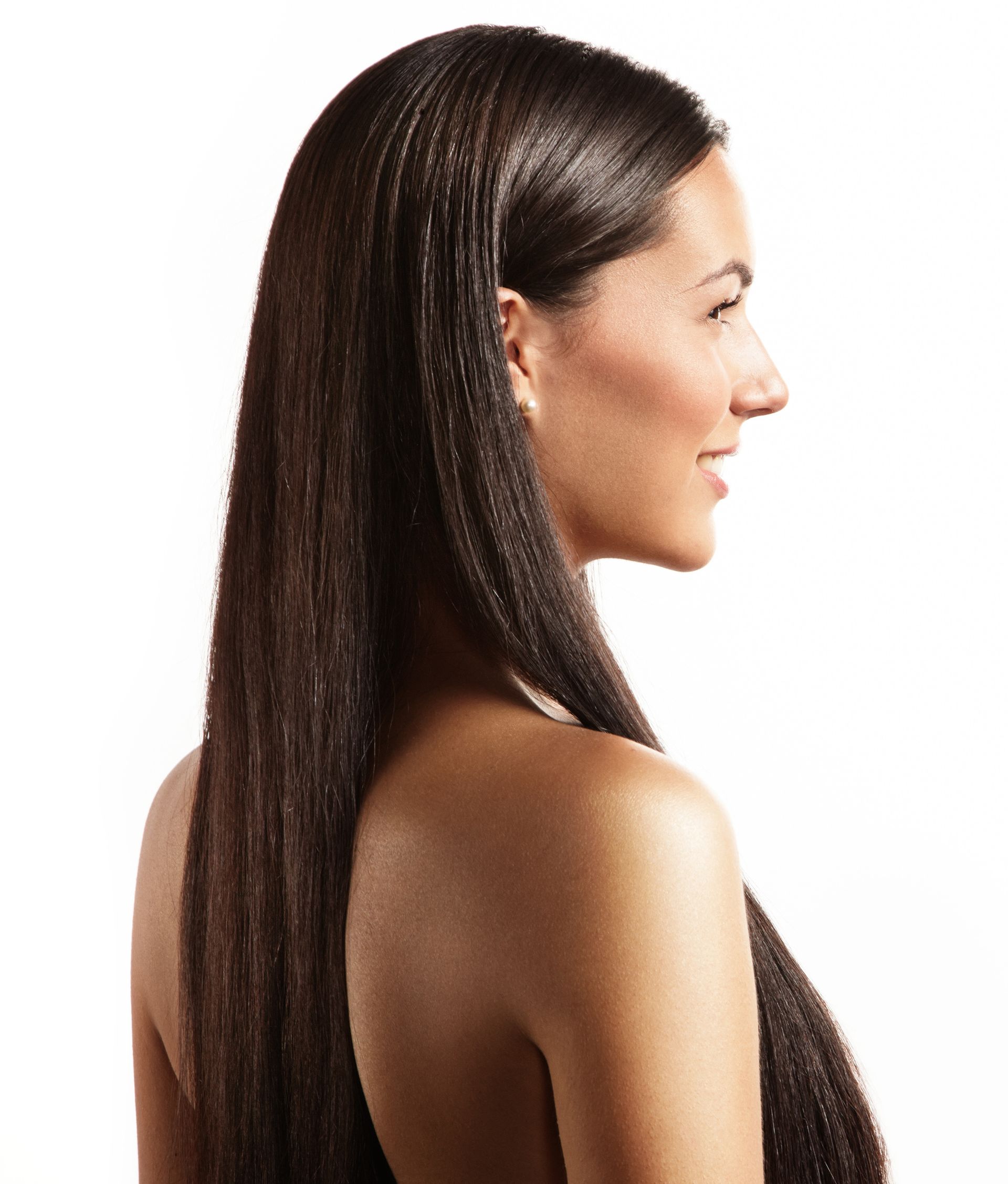 Woman with long, dark crimped hair and bare shoulders, smiling in profile against a white background.