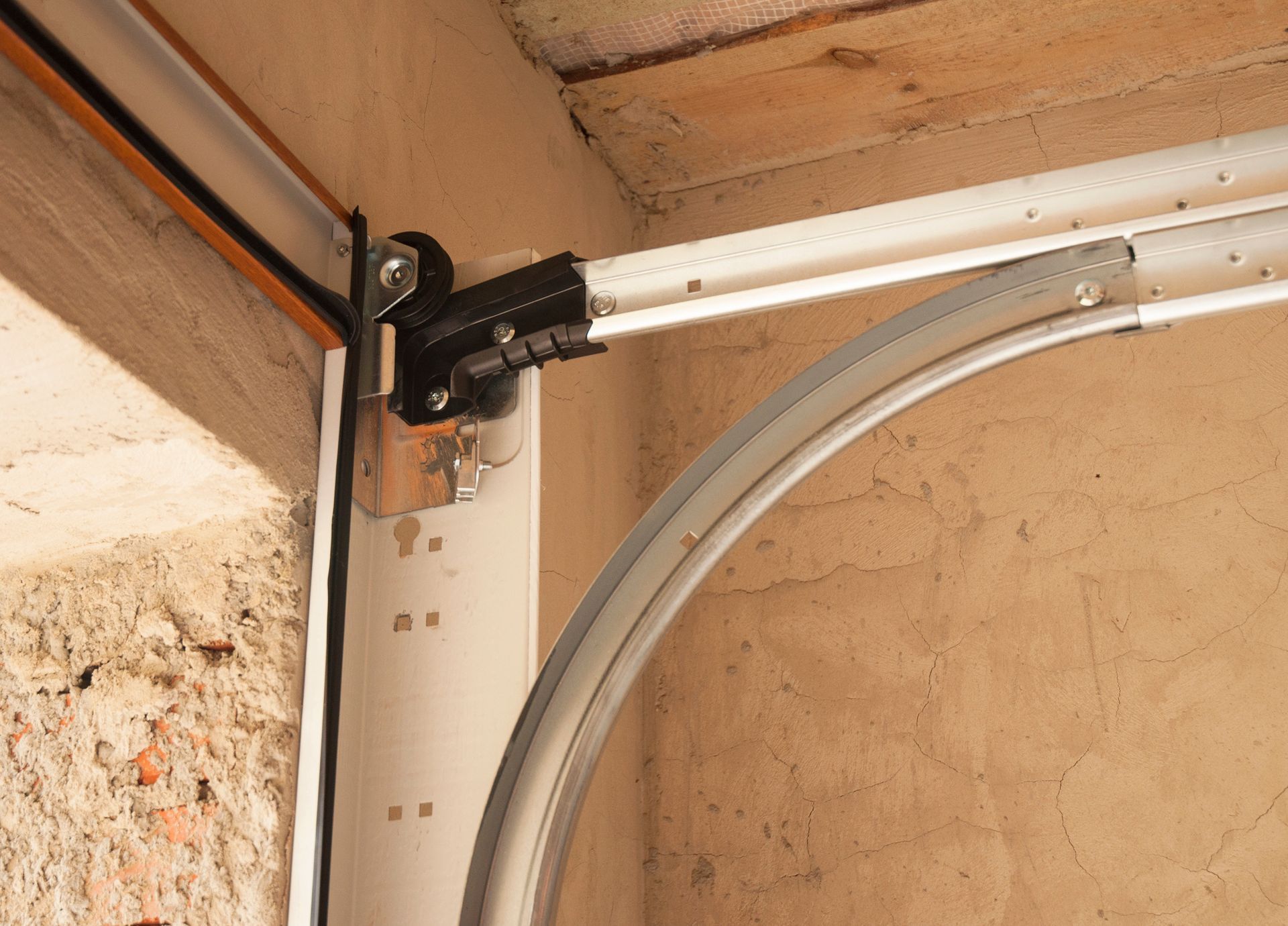 Garage door track system; curved track section connected to a straight track, mounted on a wall.