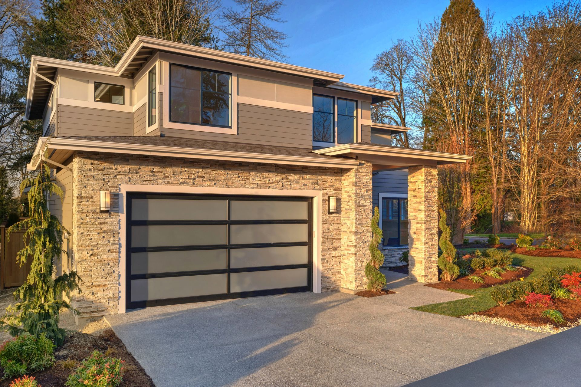 Modern two-story house with stone facade, garage, and driveway.