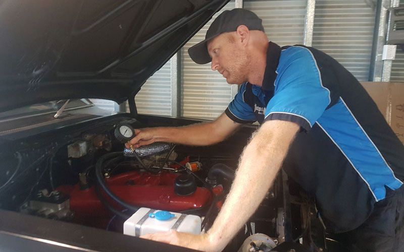 A Man Is Working on The Engine of A Car in A Garage — Automotion Mechanical In Pacific Paradise, QLD