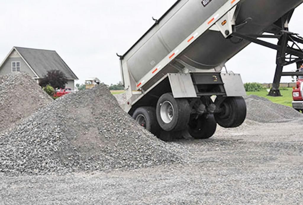 A dump truck is loading gravel into a pile.