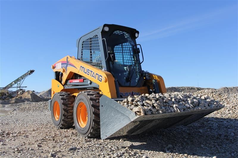 A mustang skid steer is loading rocks into its bucket