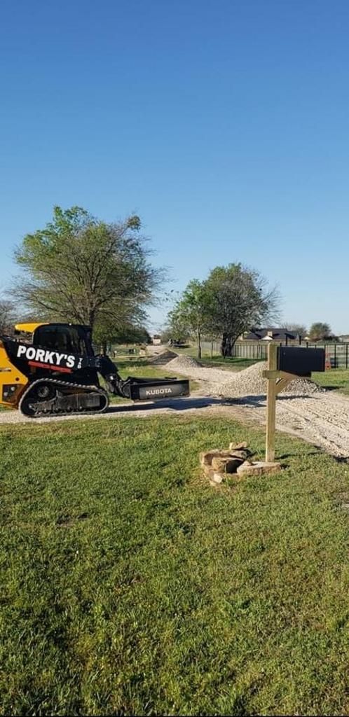 A bulldozer is driving down a dirt road next to a mailbox.