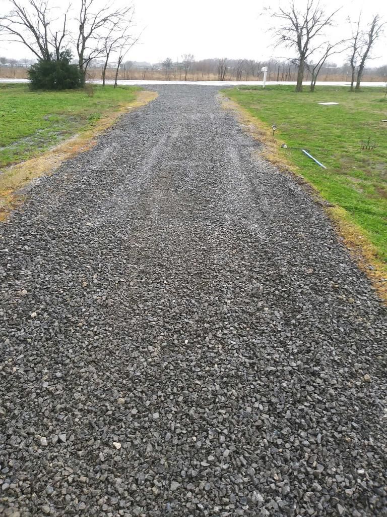 A gravel road going through a grassy field.