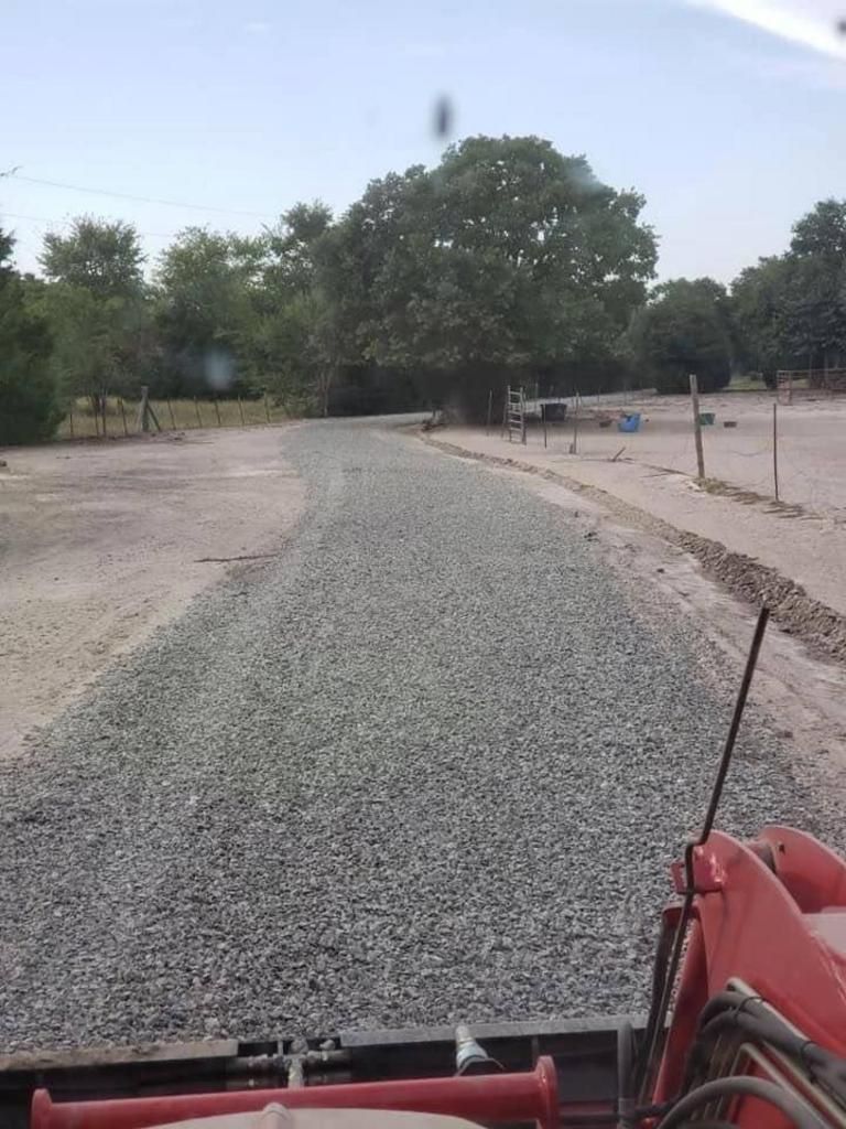 A red tractor is driving down a gravel road