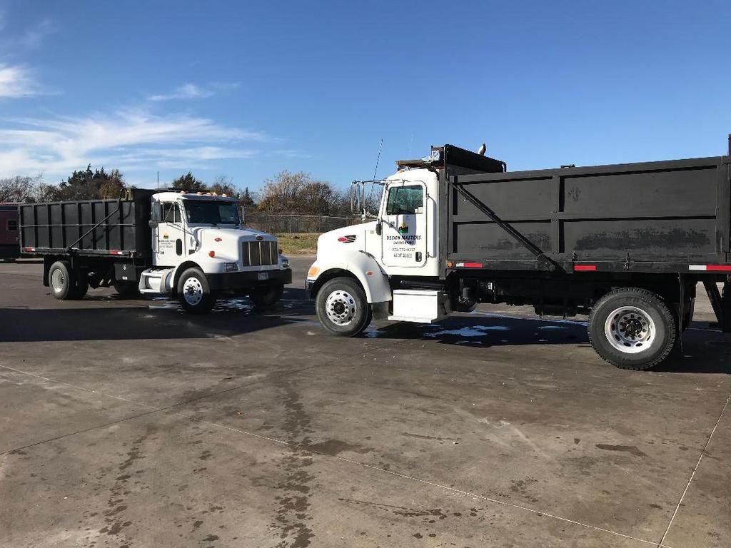 Two dump trucks are parked next to each other in a parking lot.