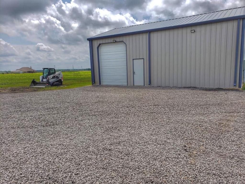 A bobcat is parked in front of a building with a garage door.