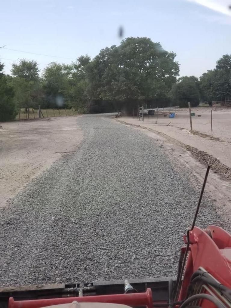 A red truck is driving down a gravel road