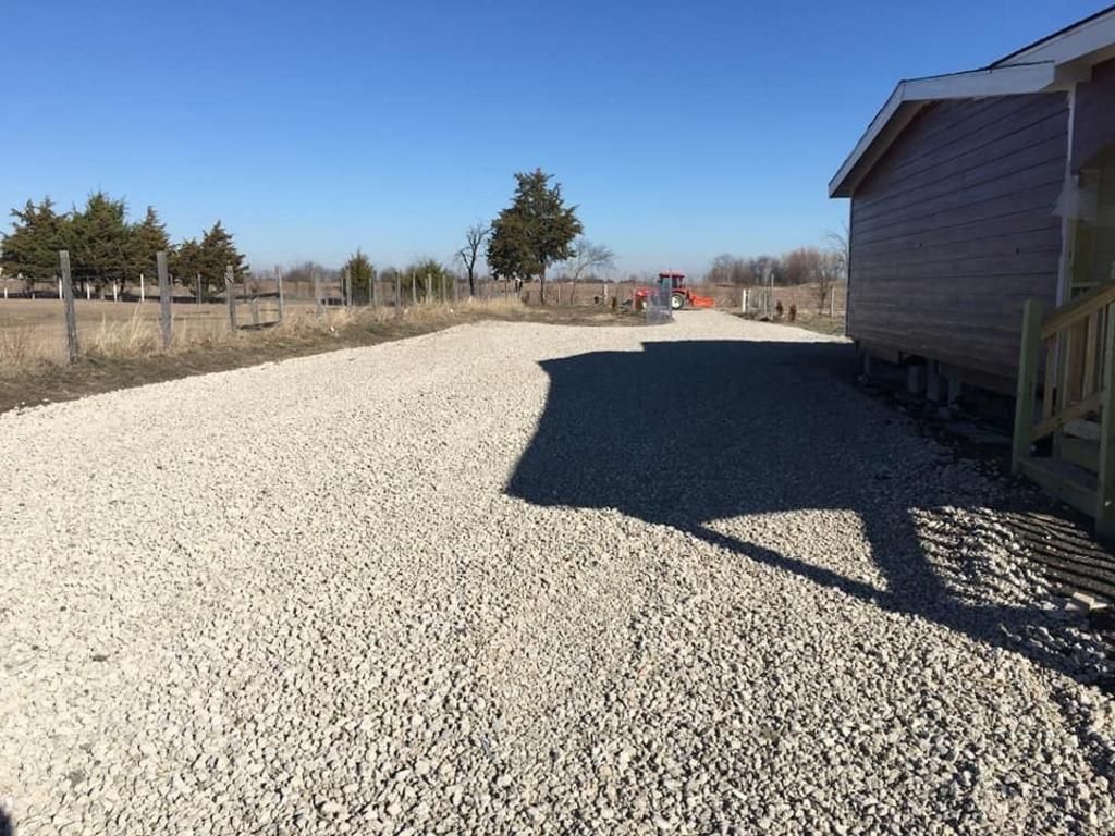 A gravel driveway with a house in the background