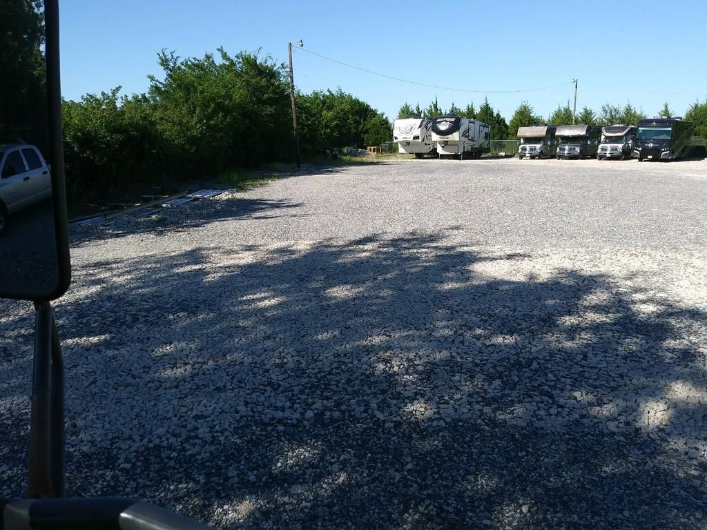 A row of rvs are parked in a gravel lot