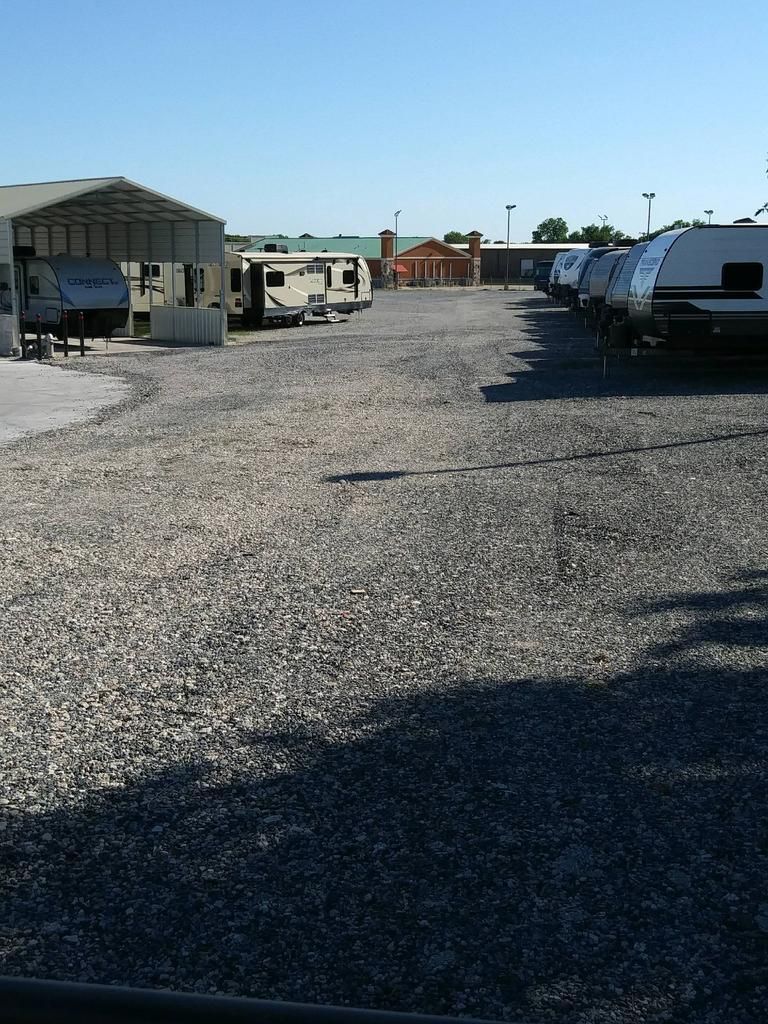 A row of rvs are parked in a gravel lot