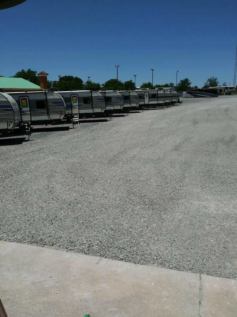 A row of trailers are parked in a gravel lot